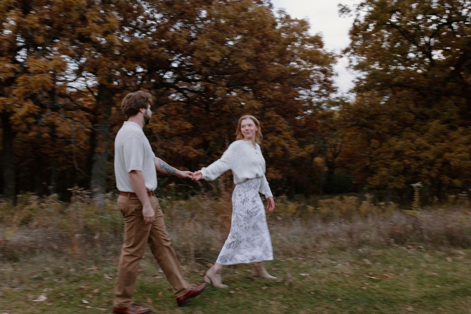 A couple embraces in a romantic dance pose against an autumn forest backdrop in Lapham Peak engagement session photos