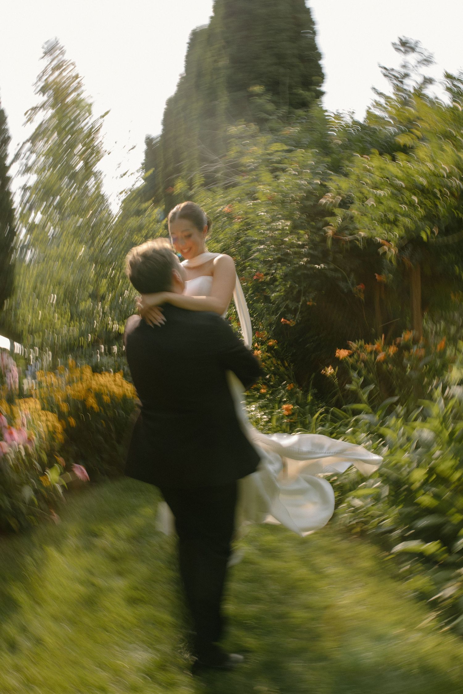 A bride and groom dancing and twirling in a garden with flowers and greenery during wedding at Gardens Wedding Center in Wisconsin