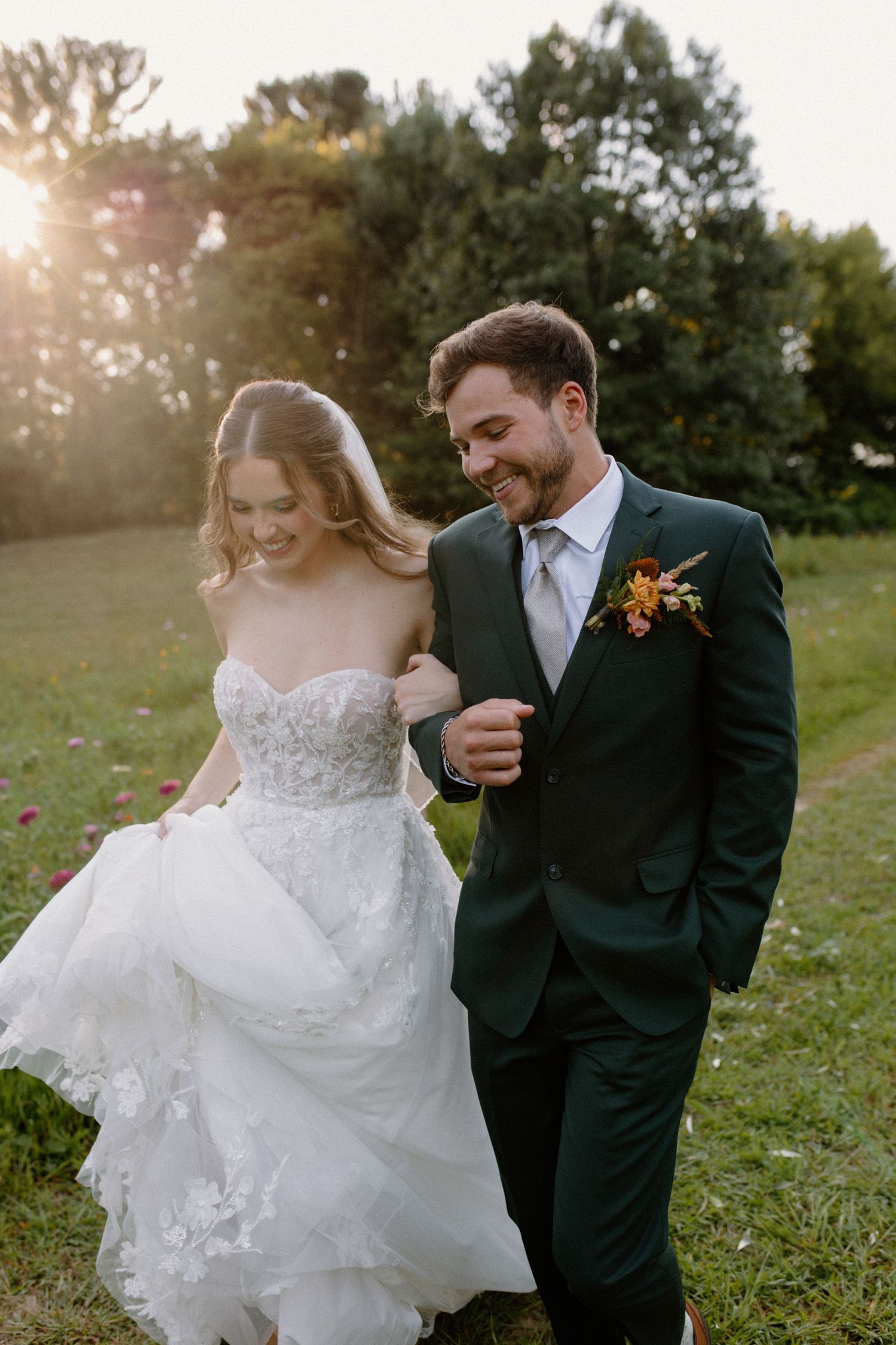 Newlyweds laugh and dance together in a flower-filled field at sunset during Wisconsin Dells farm wedding