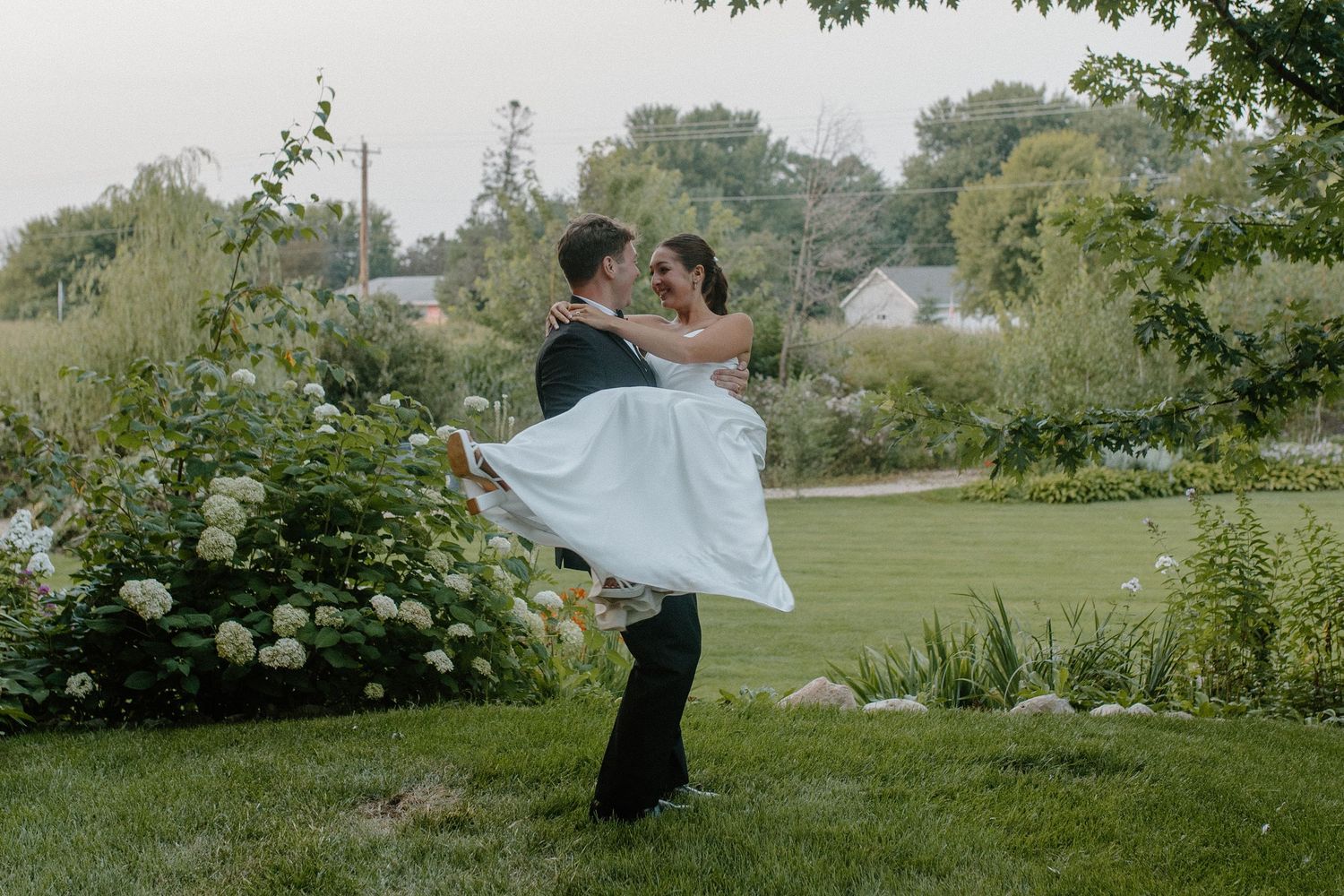 Groom spins romantically with bride in his arms in an outdoor garden setting at Gardens Wedding Center wedding