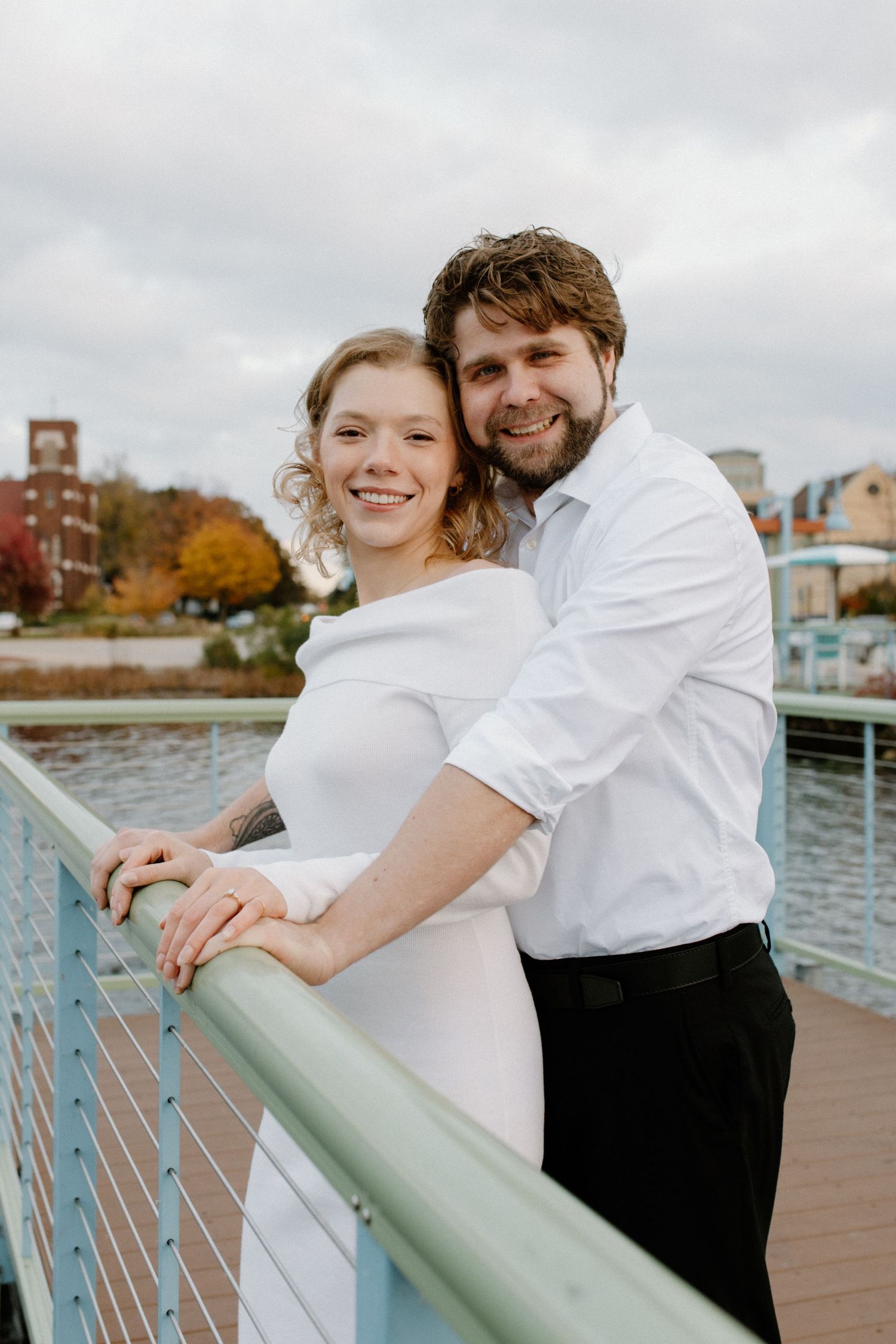 A couple shares intimate moments while leaning against a blue railing on the boardwalk in Oconomowoc engagement session
