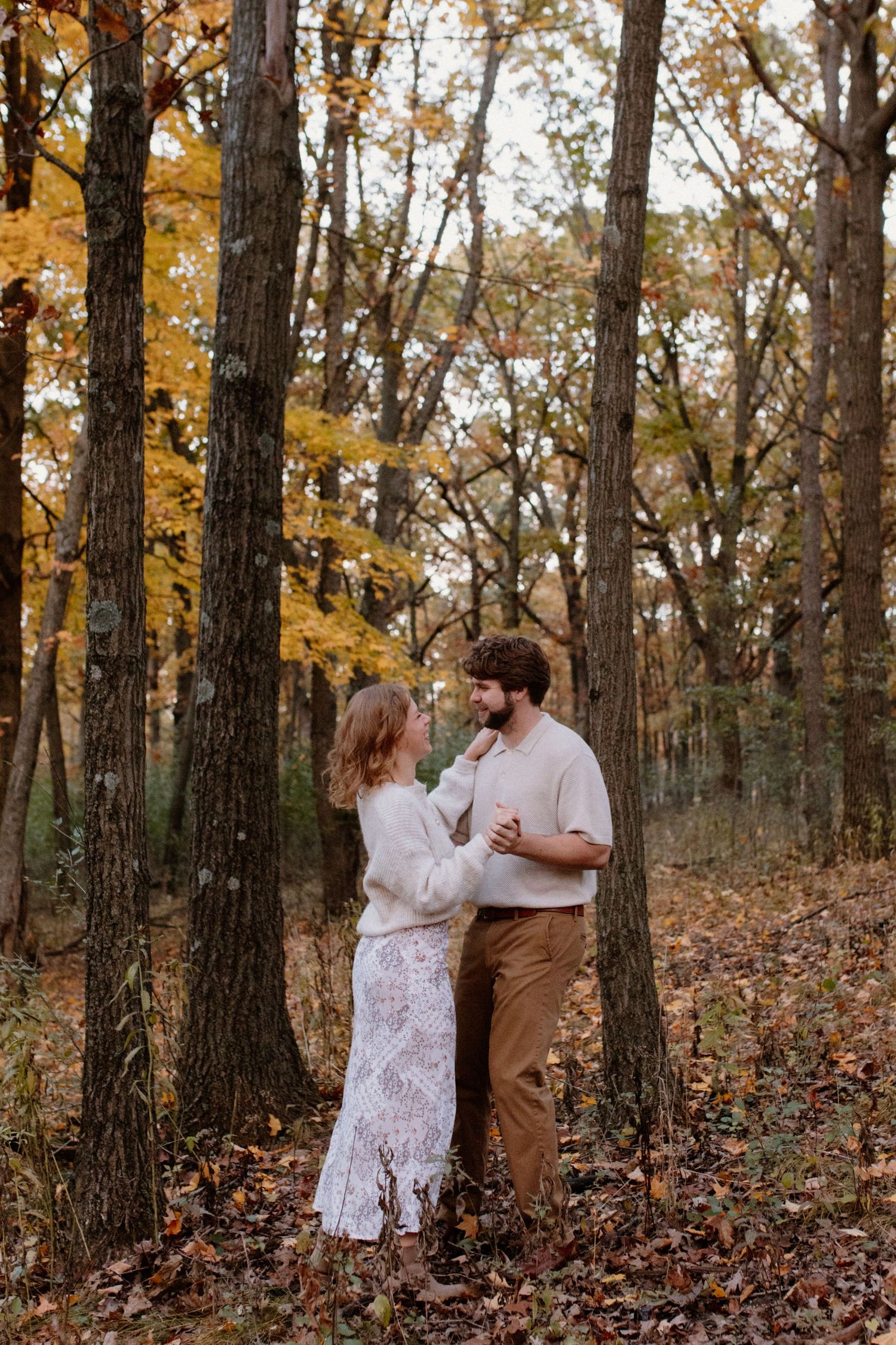 A romantic couple dancing in a wooded area with golden autumn foliage at Lapham Peak engagement session