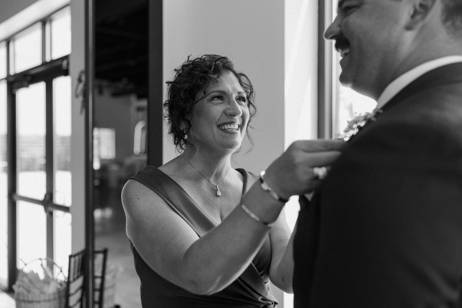 Black and white candid moments captured in an indoor venue with natural window light.