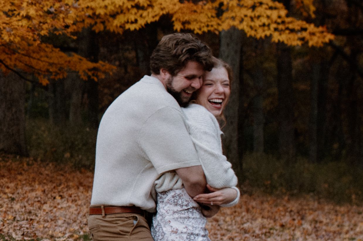 A joyful couple sharing an intimate moment surrounded by golden autumn trees during Wisconsin engagement session