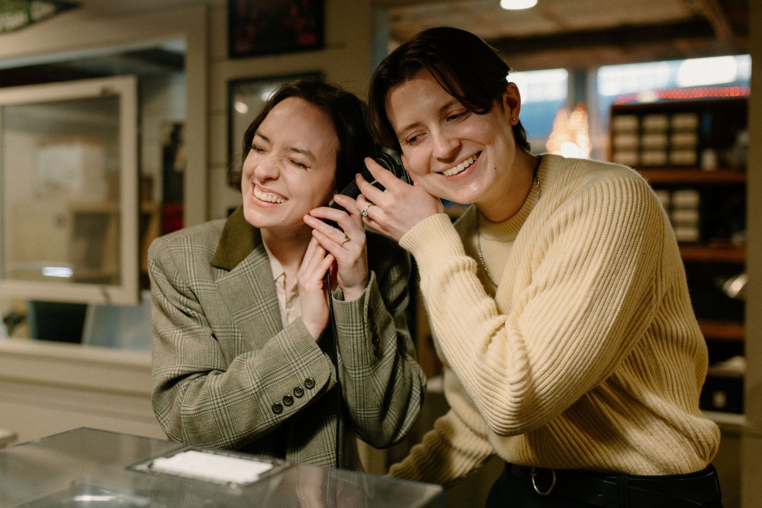 Two happy women smiling and trying on rings at a jewelry store display case.