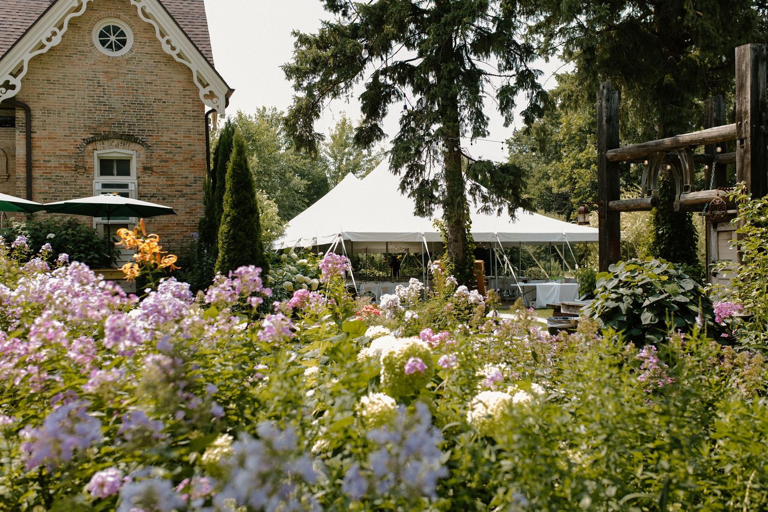 A garden wedding venue with colorful flowers and a white tent surrounded by stone buildings in Wisconsin