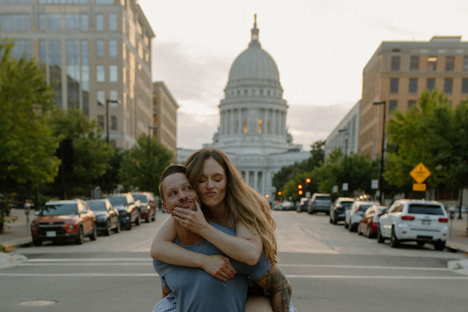 Couple shares romantic moment with Madison State Capitol building visible in background for couples photography session