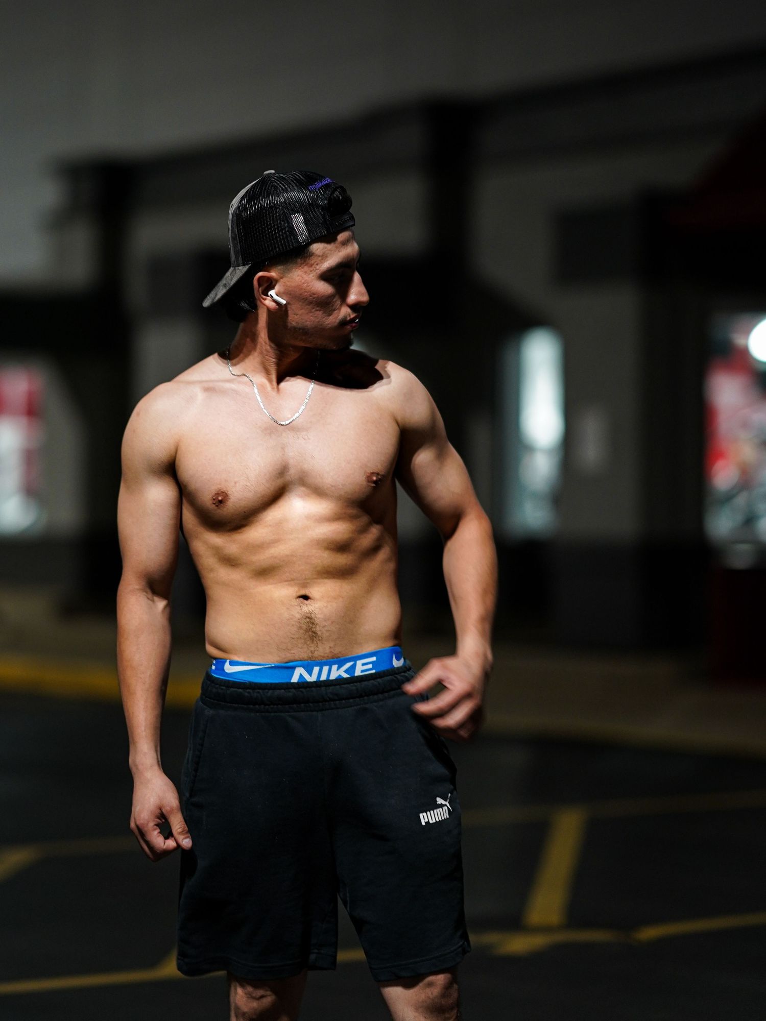 Athletic figure wearing Nike and Puma gear photographed in shadowy parking structure.