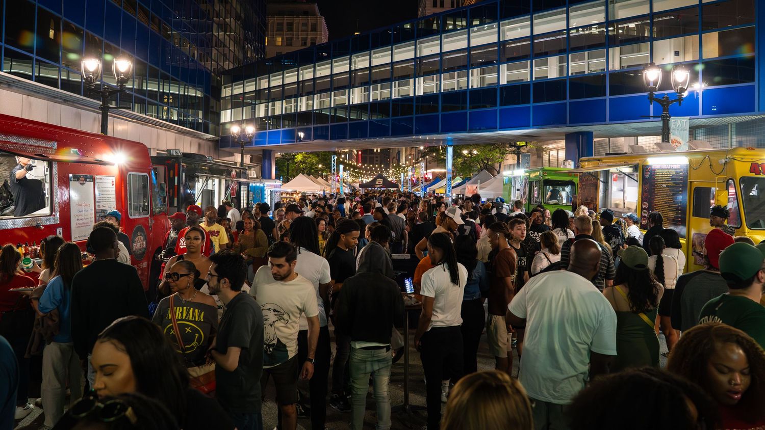 Dense crowd of festival attendees gathered between buildings at night.