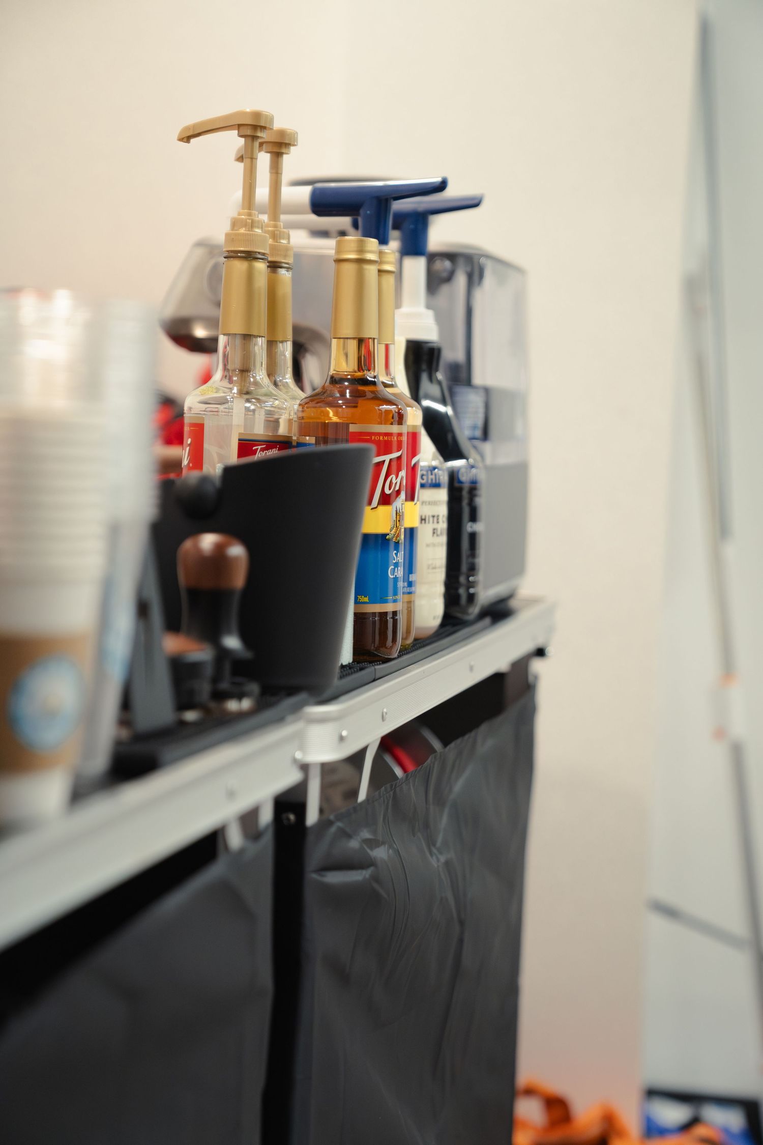 Coffee bar shelving displaying various bottles and containers for drink preparation.