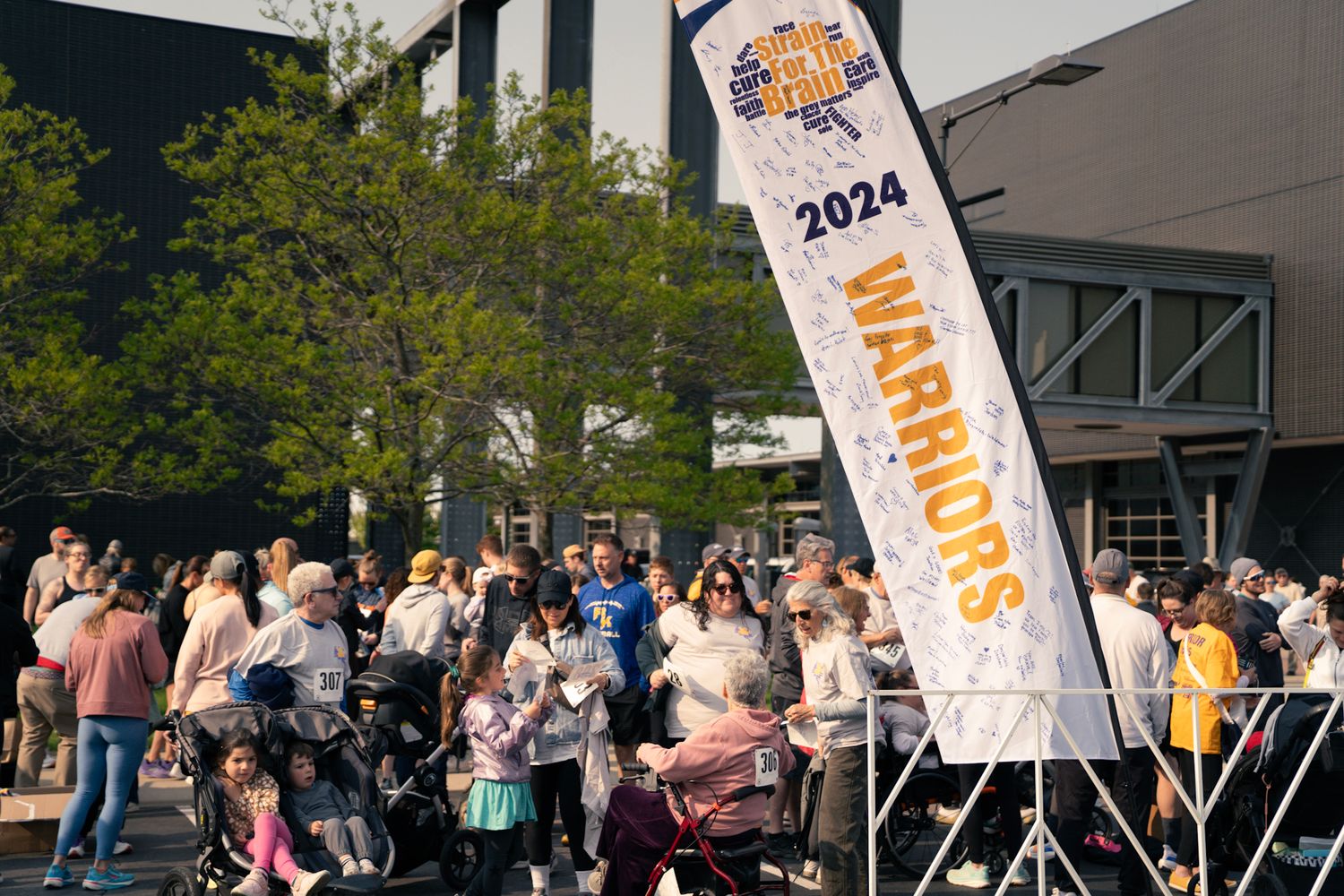 Festival crowd gathered near Warriors 2024 banner outside venue.