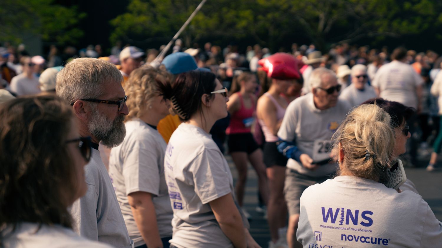 A crowd of participants gathered at an outdoor event wearing casual attire and baseball caps.