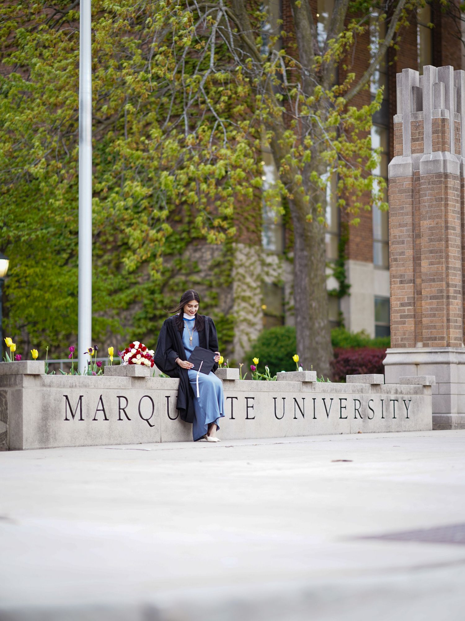 View of Marquette University campus entrance sign with brick columns and greenery.