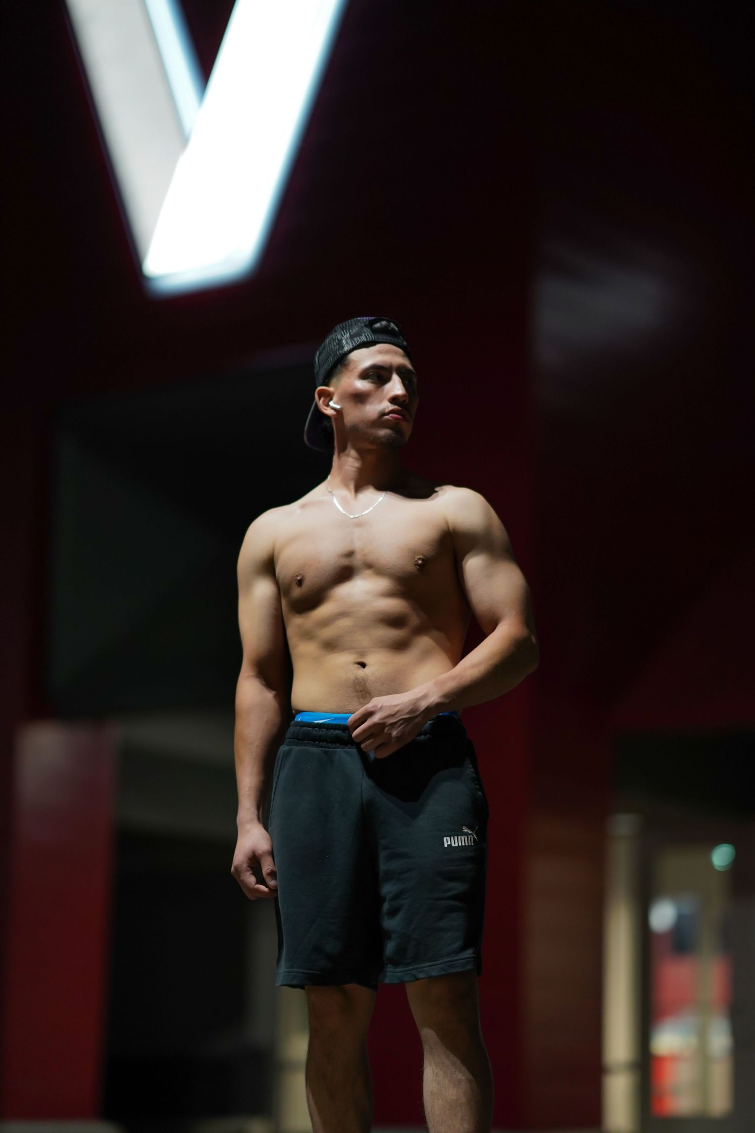 Athletic figure in dark shorts exercising in a dimly lit indoor space.