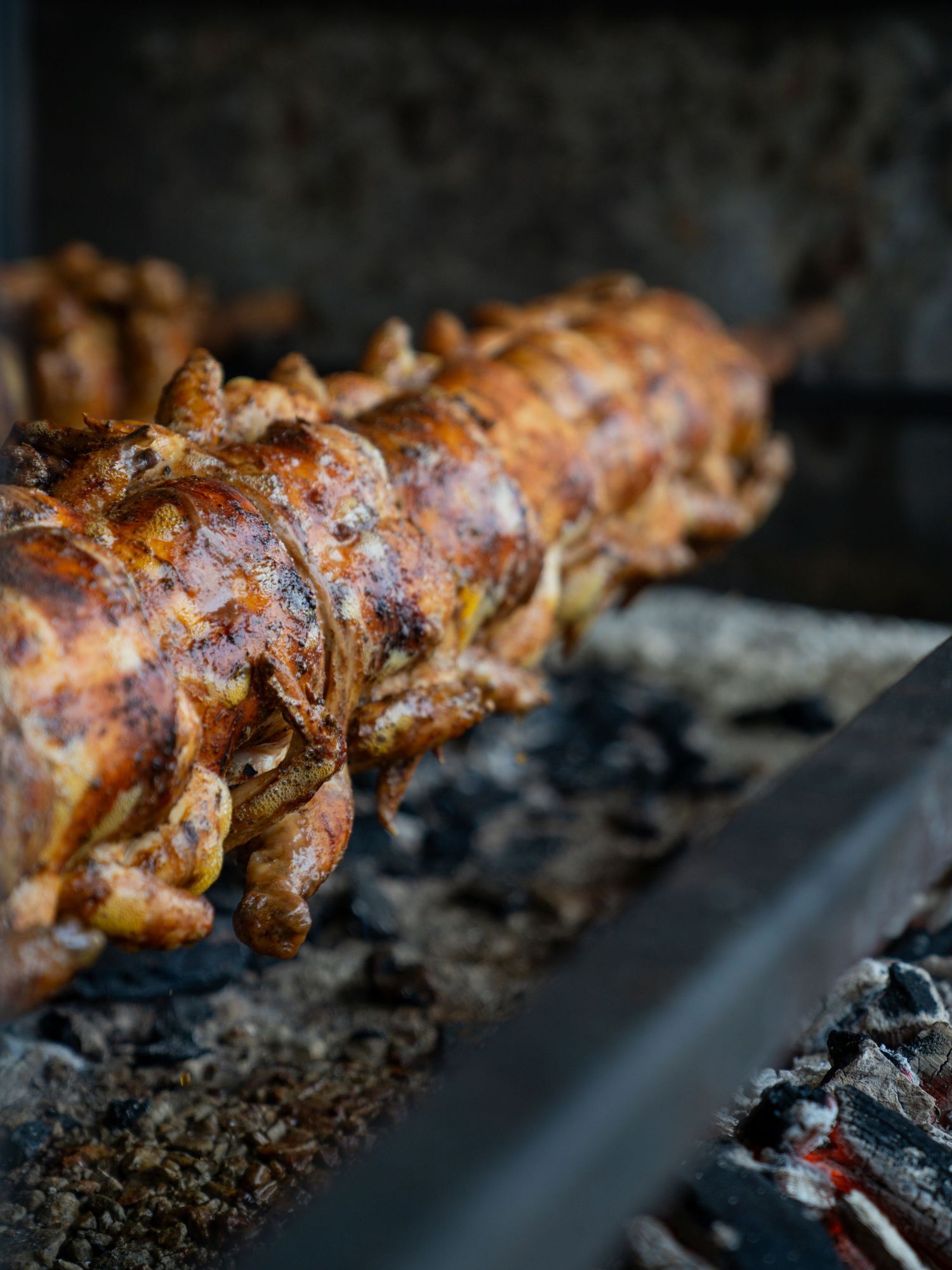 Close-up view of grilled meat on a barbecue grill with glowing charcoal embers.