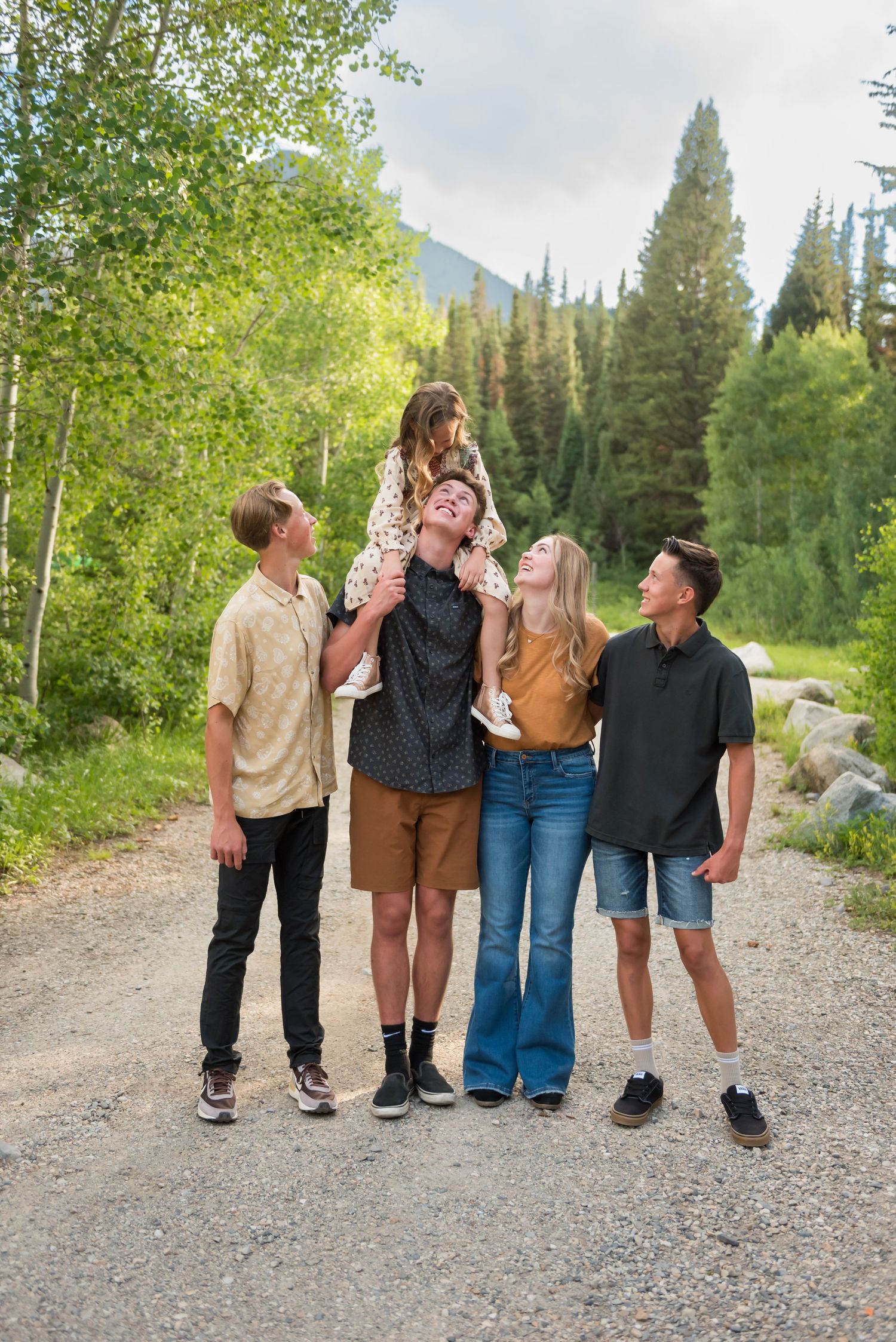 Group of friends standing on mountain path showing their backs while enjoying scenic wilderness view.