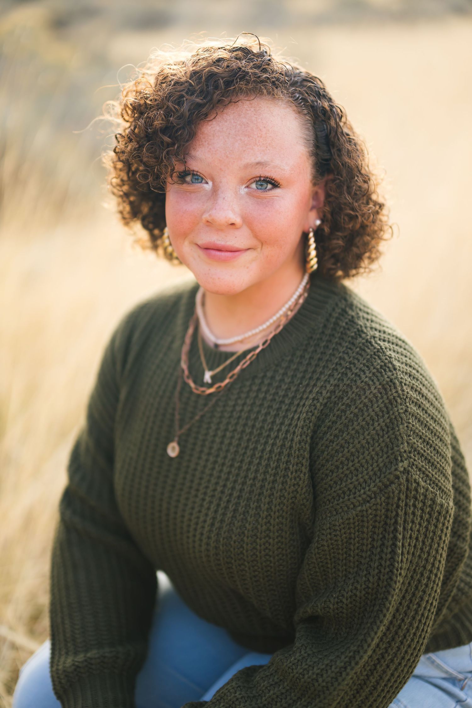 Person in a dark green sweater poses for a portrait against a golden outdoor background in salt lake city utah during family photoshoot