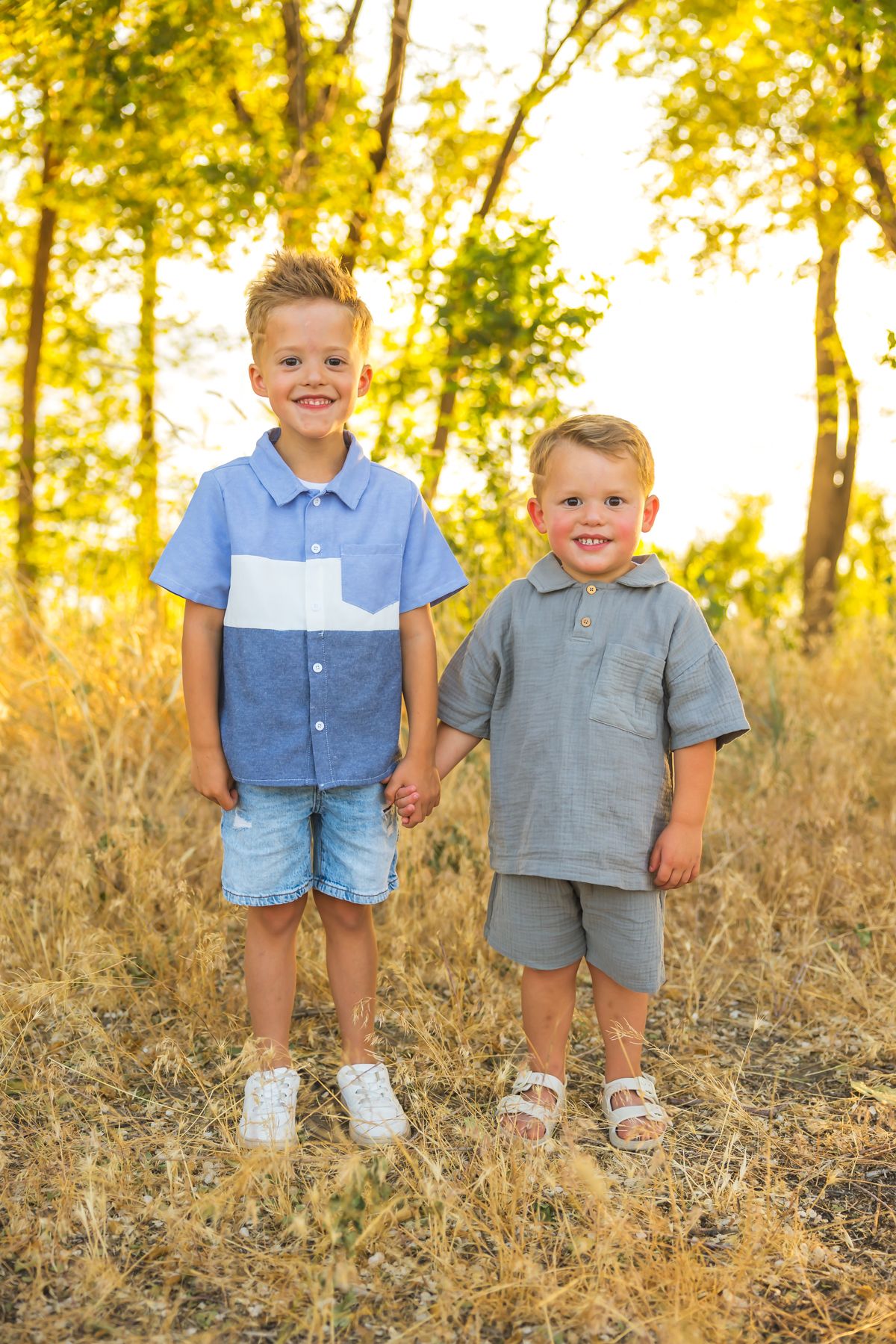 Children posing together on a hillside wearing coordinated blue and gray outfits.
