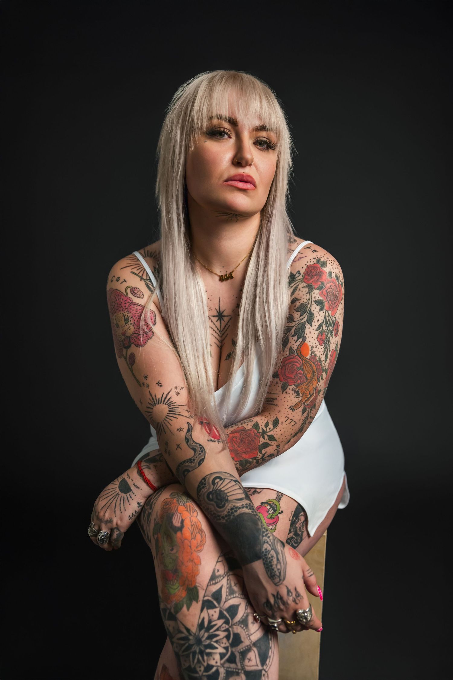 Artistic portrait series showing heavily tattooed arms in various poses against dark background.