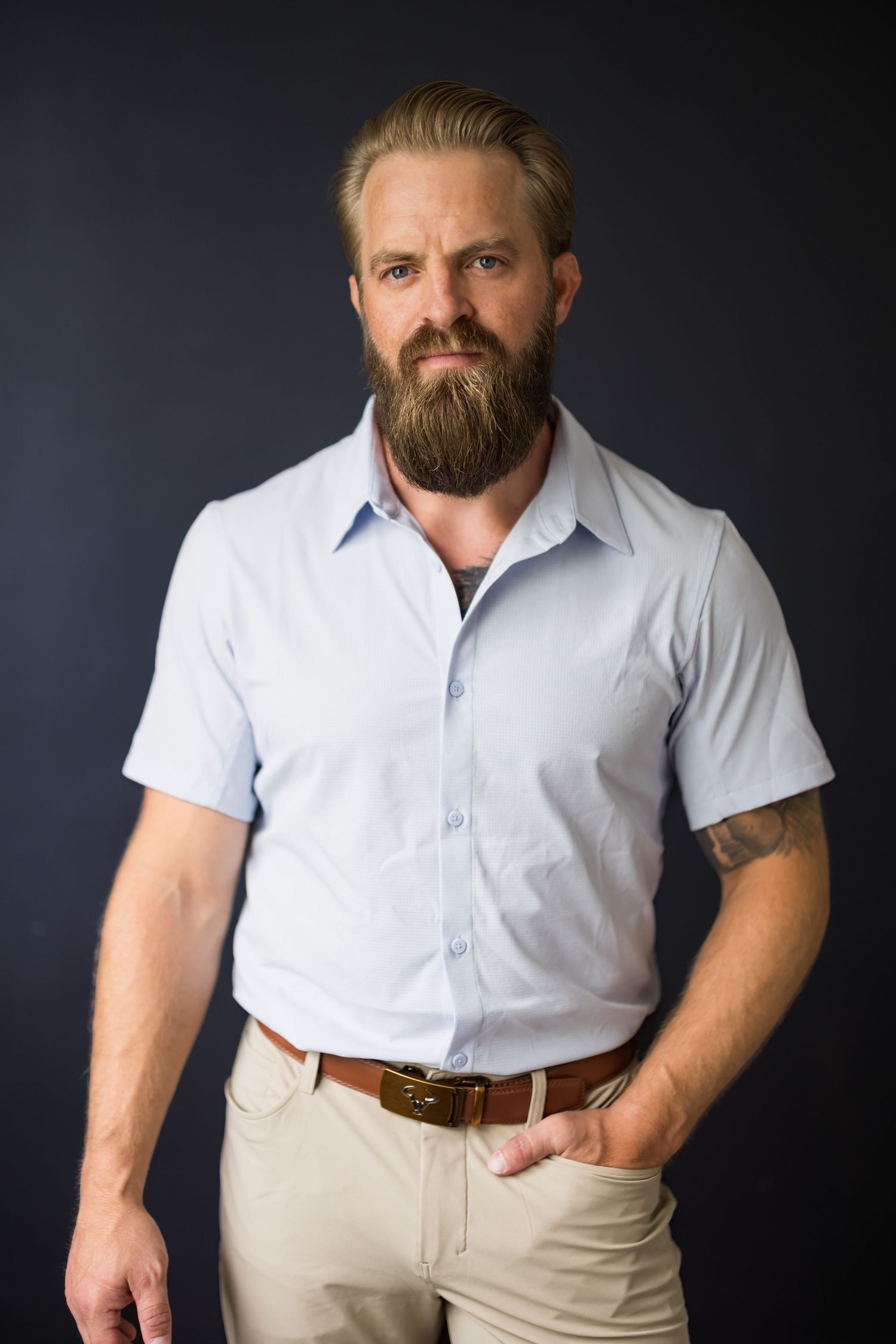 Studio portrait of person in white button-down shirt against dark background.