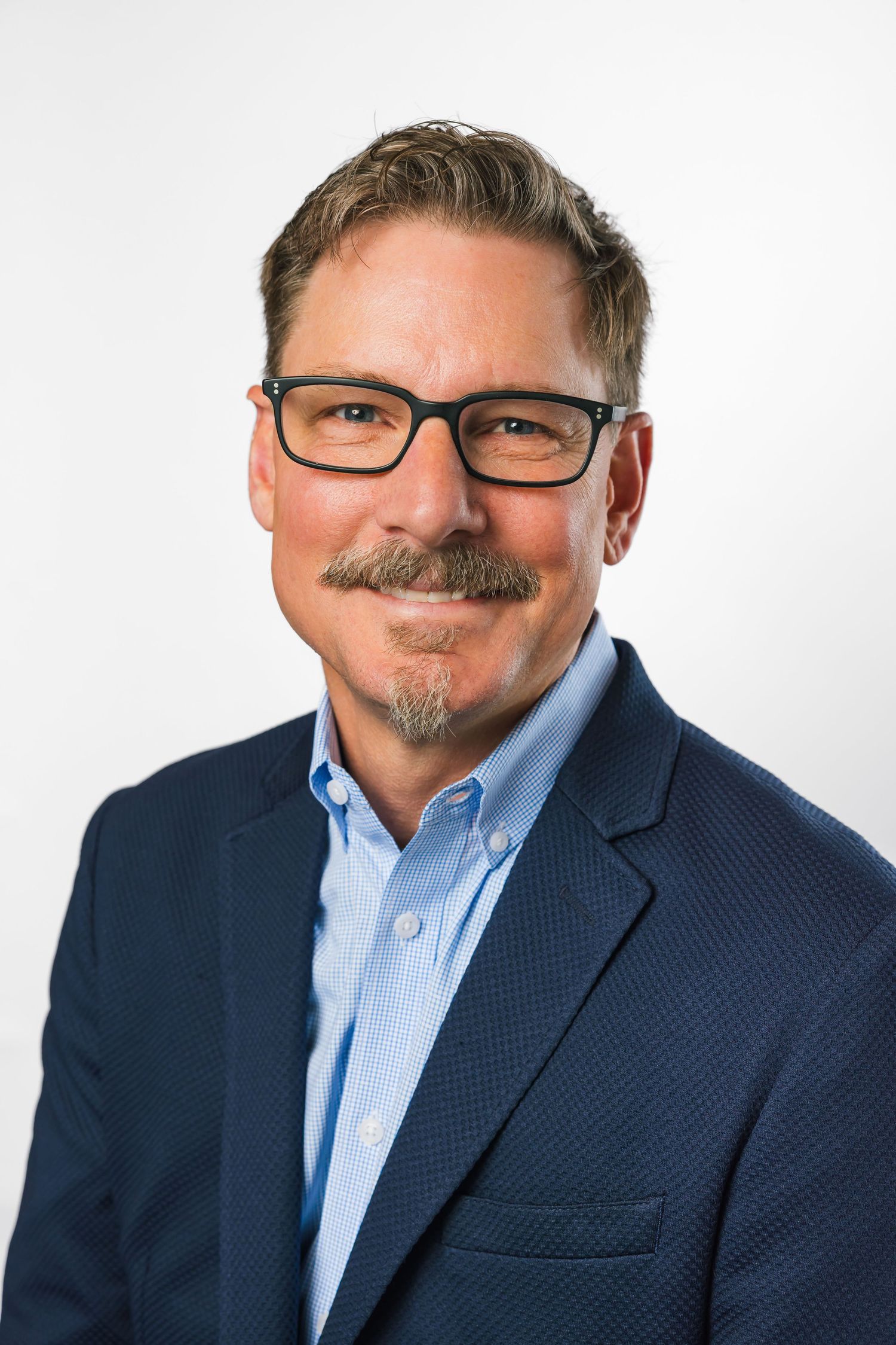 Professional headshot series of person in navy blazer and glasses against white background.