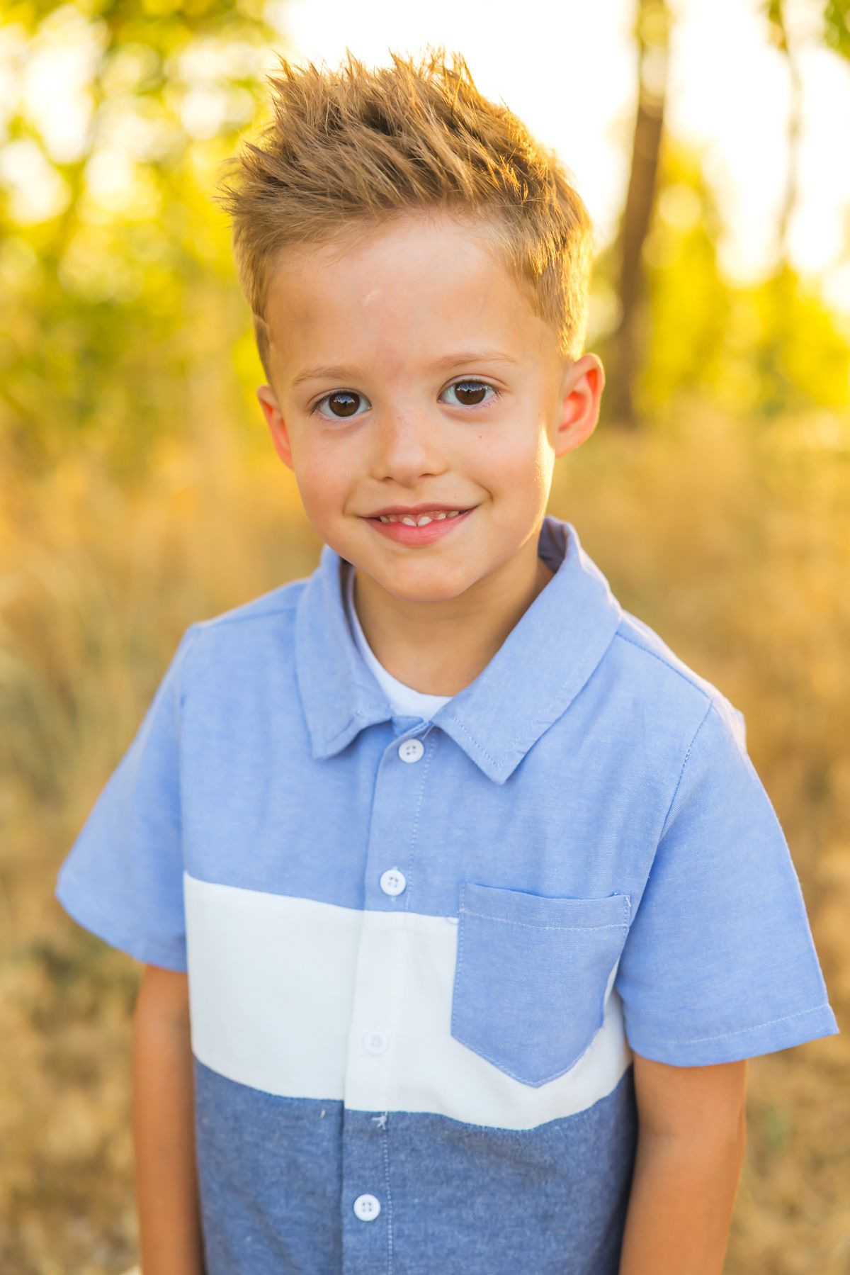 Portrait of child wearing blue color block polo shirt outdoors.