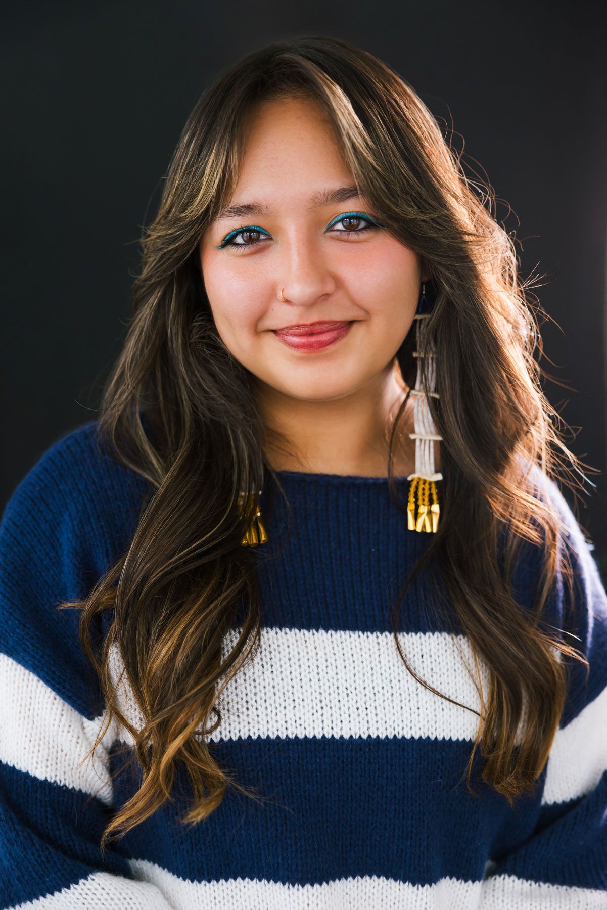 Woman wearing navy and white striped sweater poses against dark background.