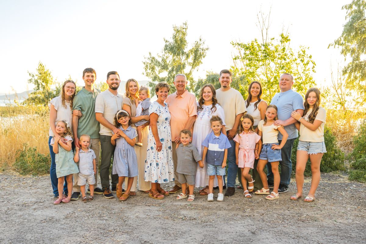 Extended family group photo with multiple generations standing together outdoors in coordinated outfits.