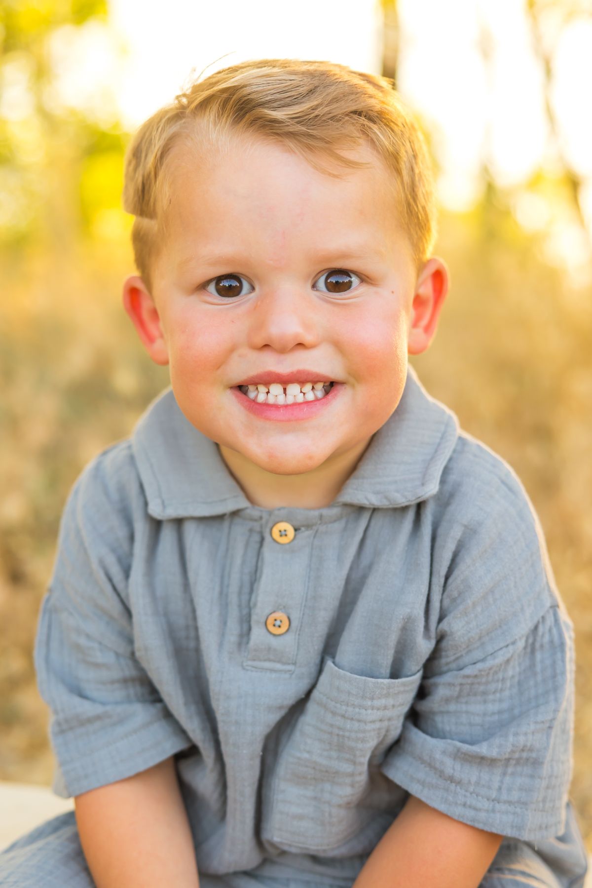 Close up portrait of child in gray shirt with bright smile.