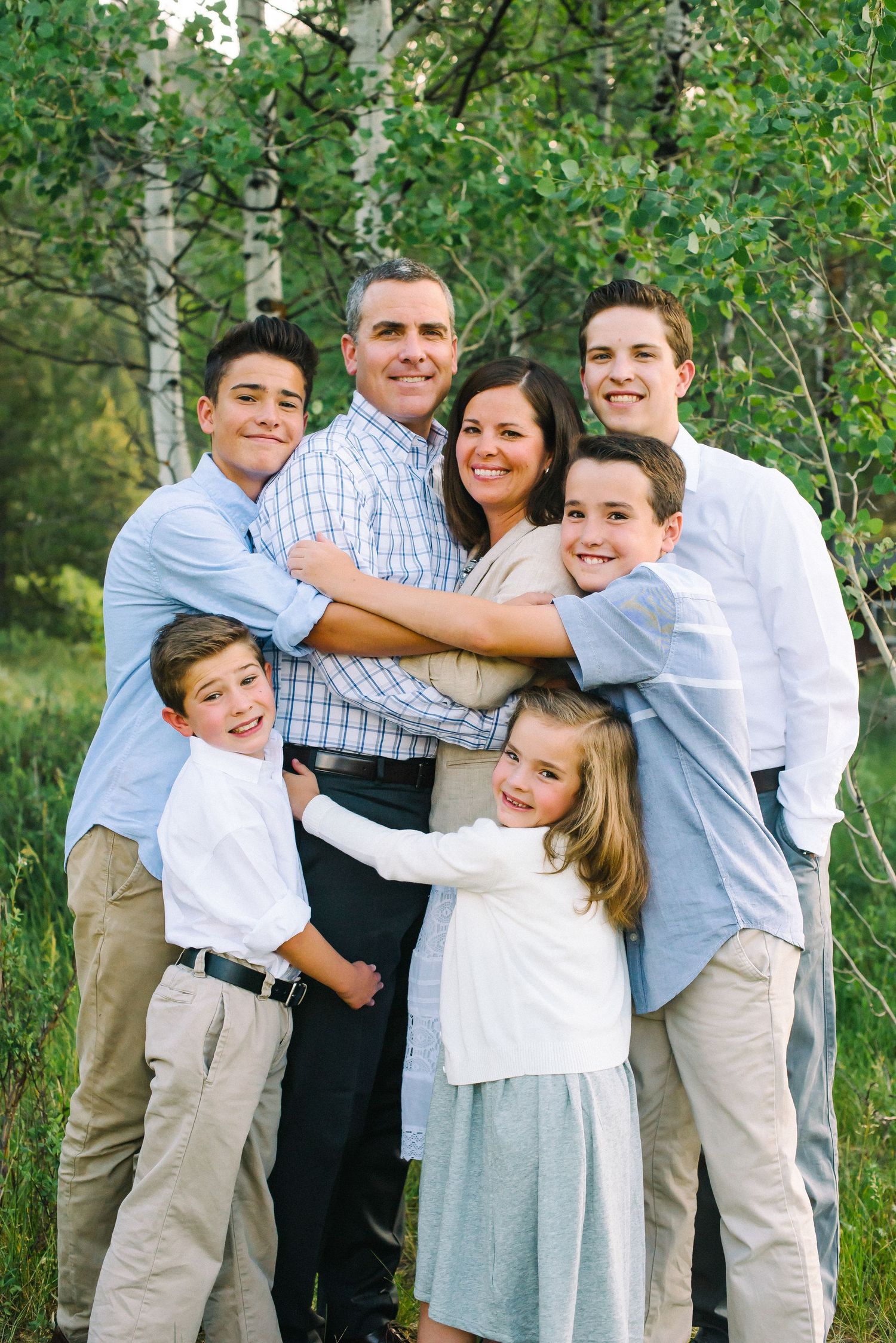 Group portrait of family members posing together outdoors with birch trees in background.