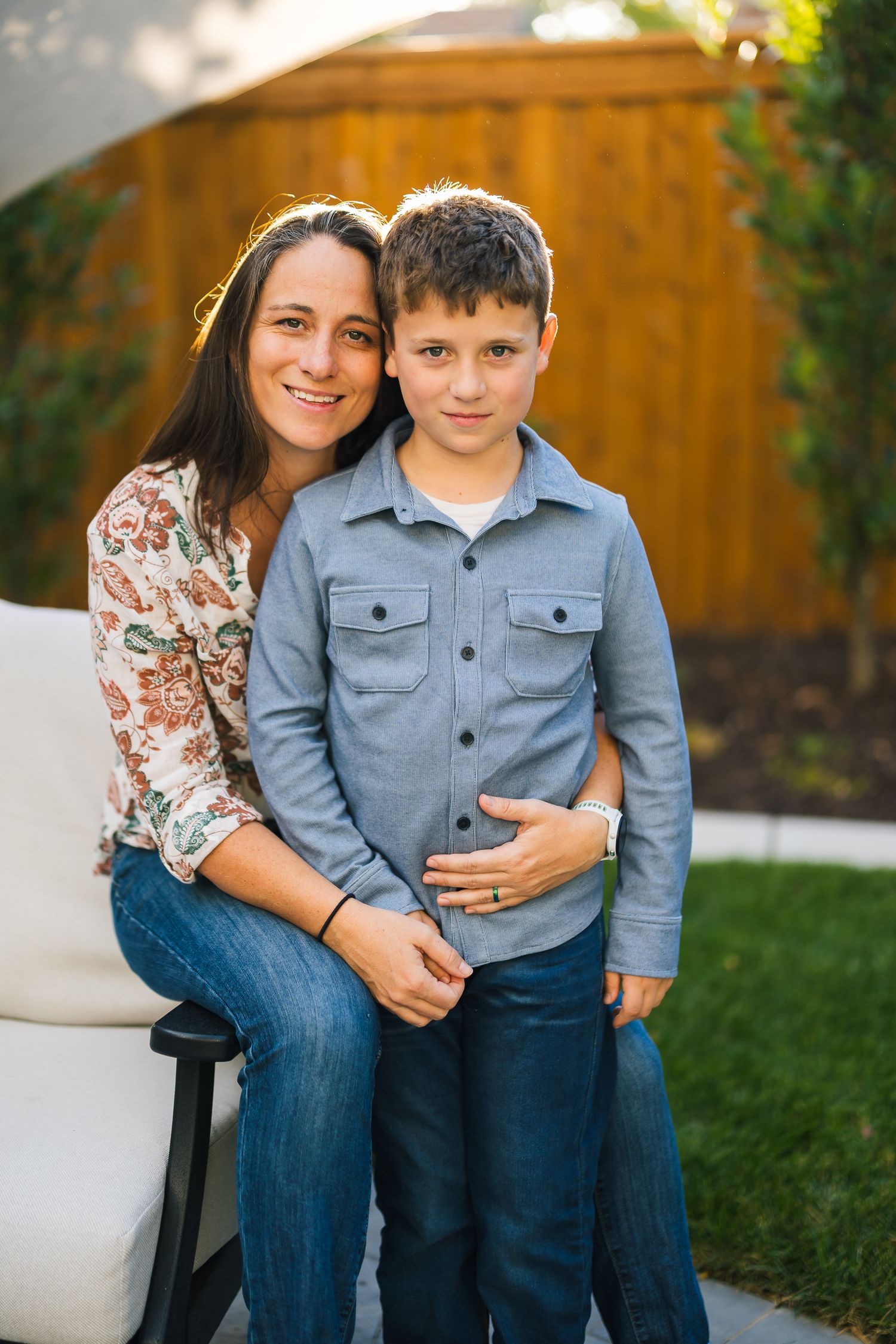 Intimate family portrait outdoors with a cozy seating arrangement and wooden fence backdrop.