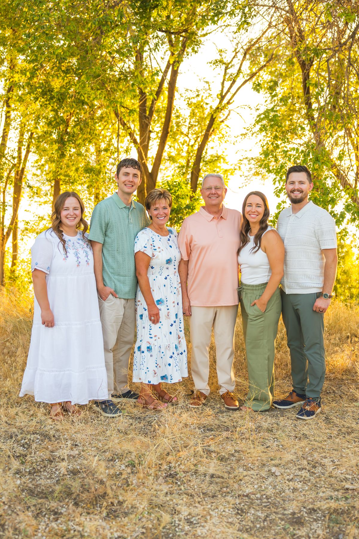 Large family portrait with multiple generations in pastel and neutral colored clothing.