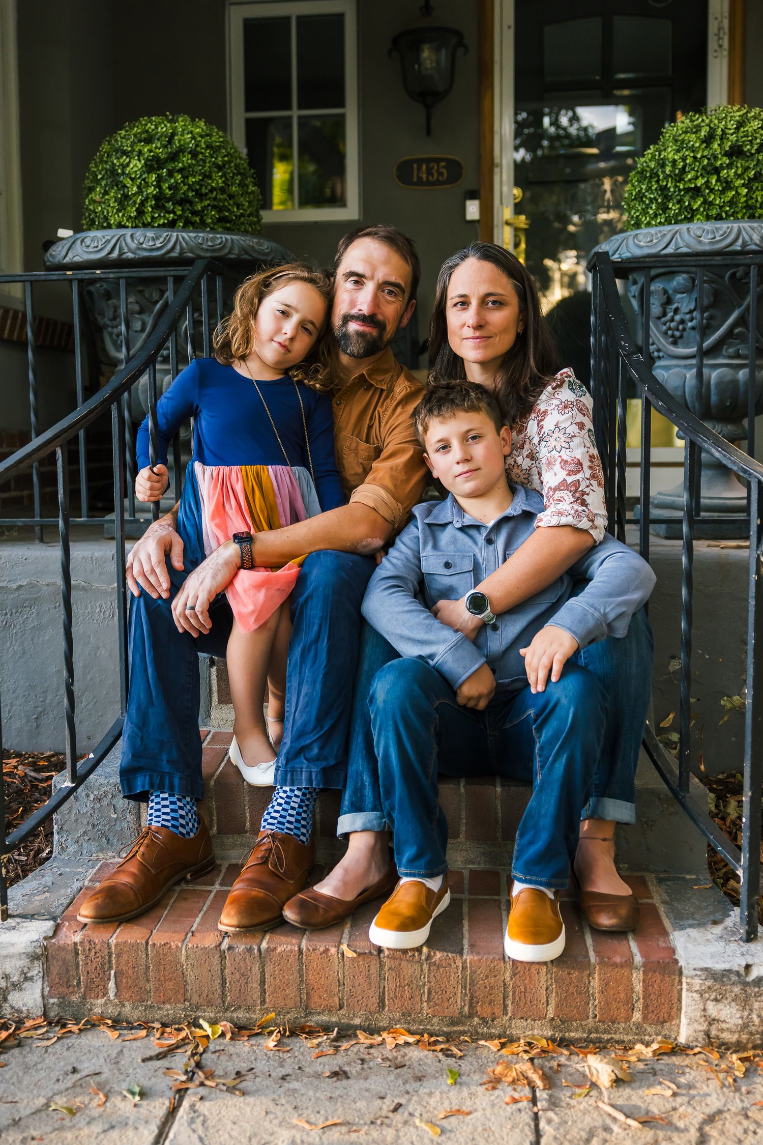 A family poses for a portrait on their home's front steps during golden hour.