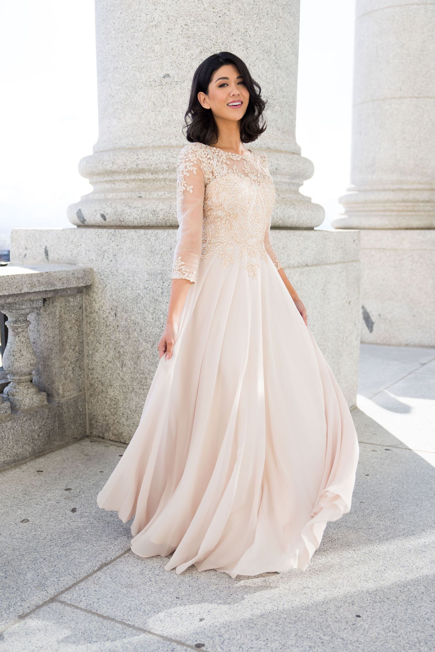Elegant sweeping bridal photos in blush pink gown against classical stone columns and architecture.