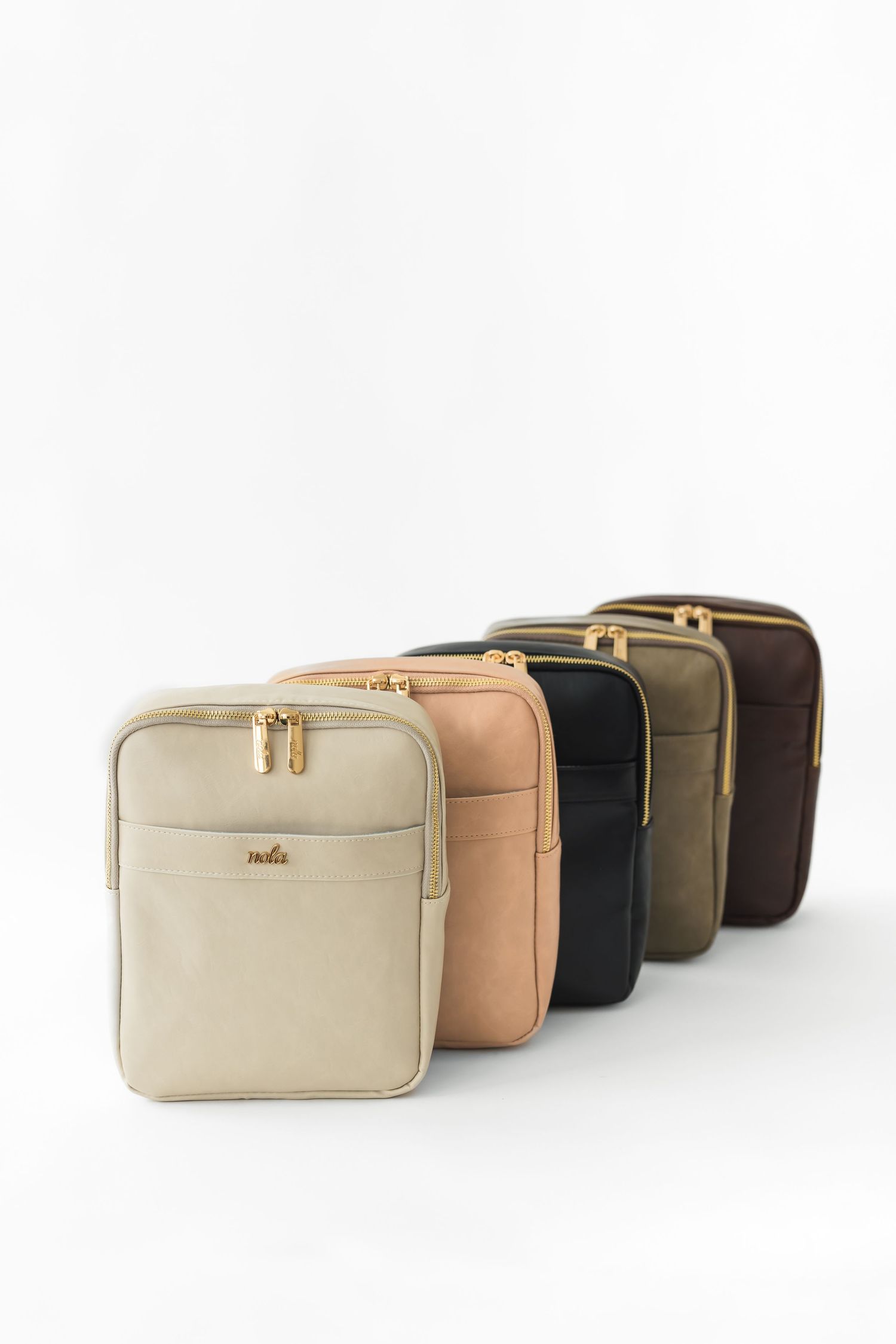 Four leather cosmetic bags in different neutral colors - beige, tan, black, and brown - lined up in a row.
