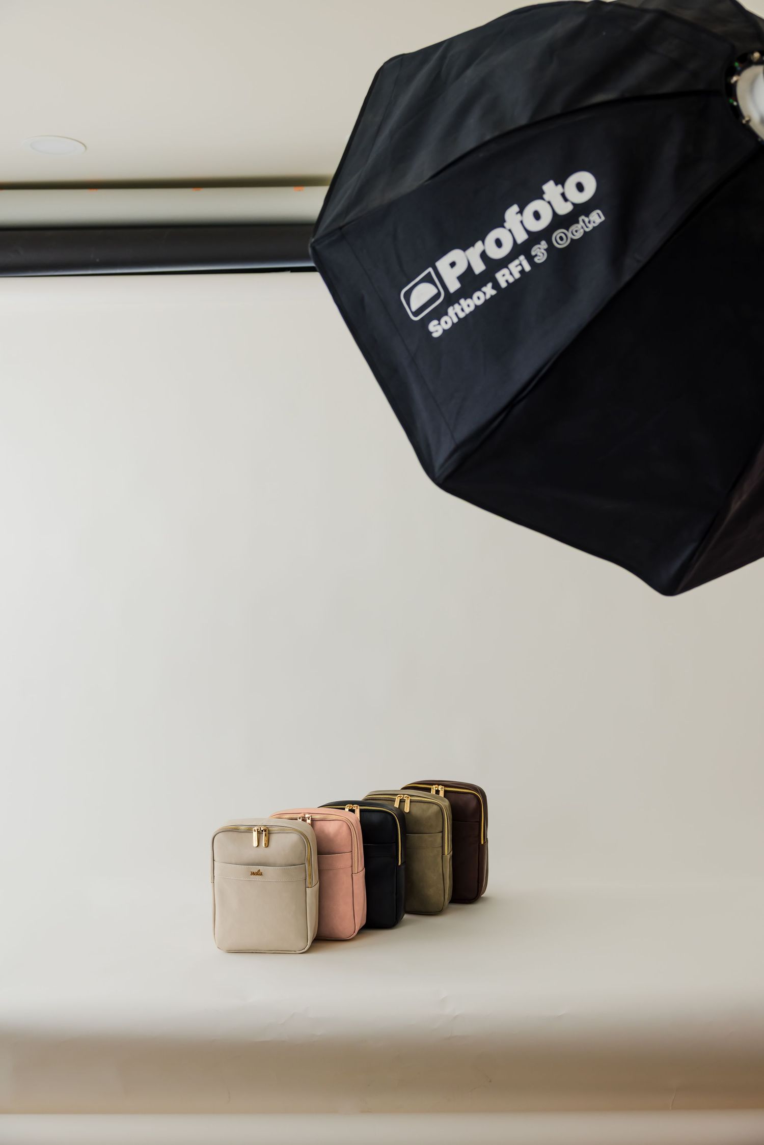 Professional photography lighting setup with black softbox umbrellas and neutral colored accessories on a white surface.