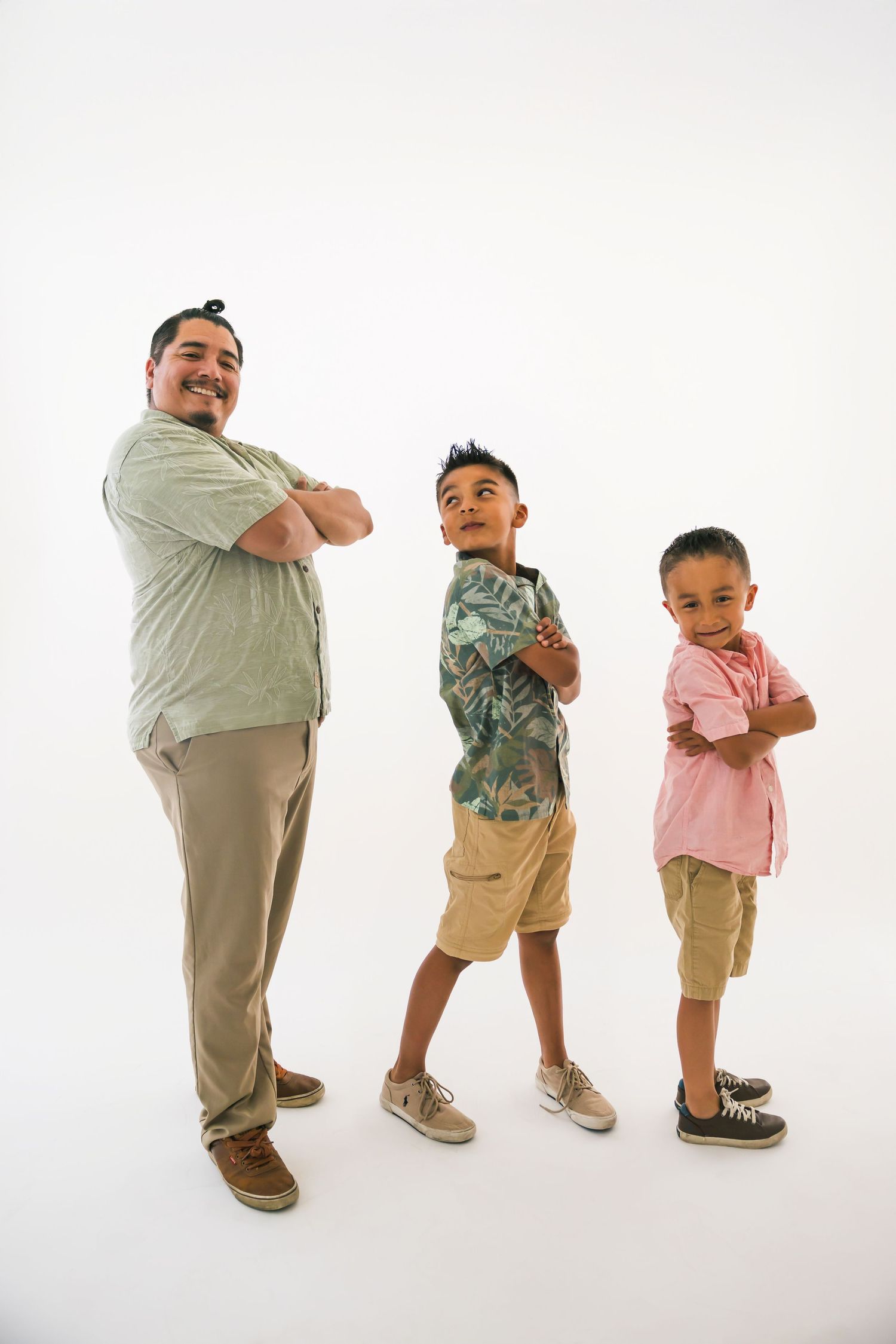 Three people stand in a row with crossed arms, wearing casual clothing against a white background.