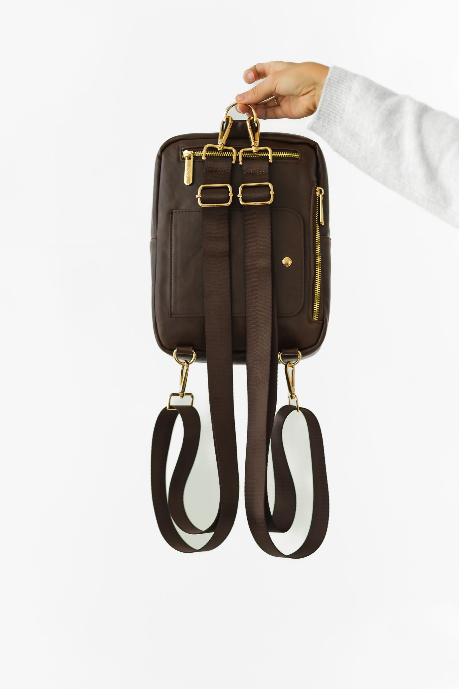 Brown leather backpack straps with brass hardware and buckles shown from different angles on white background.