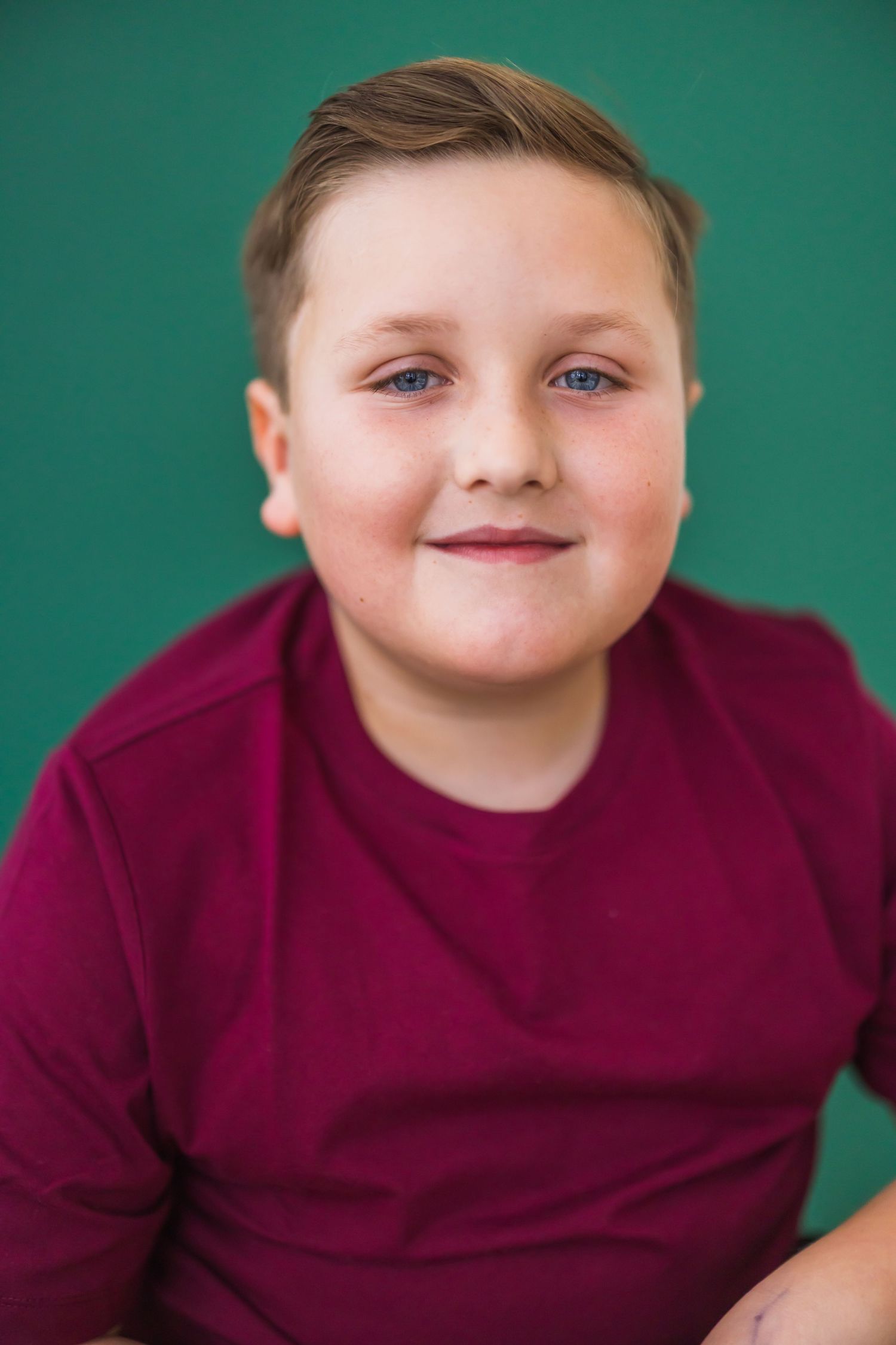 A sequence of five similar photos showing a child in a burgundy sweater against a teal background.