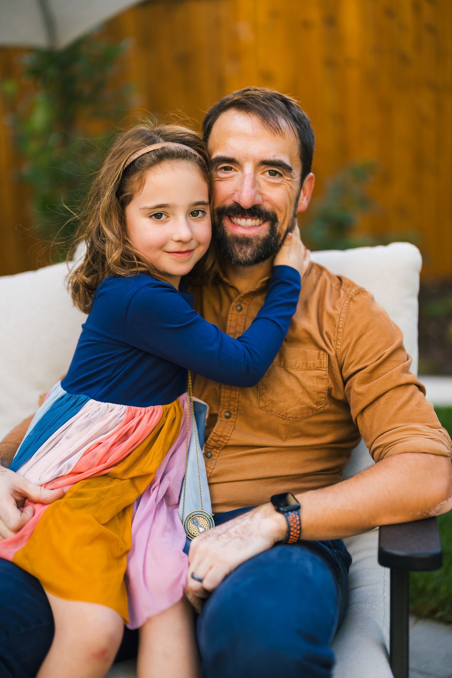 Loving family moment captured on outdoor patio furniture with warm natural lighting.