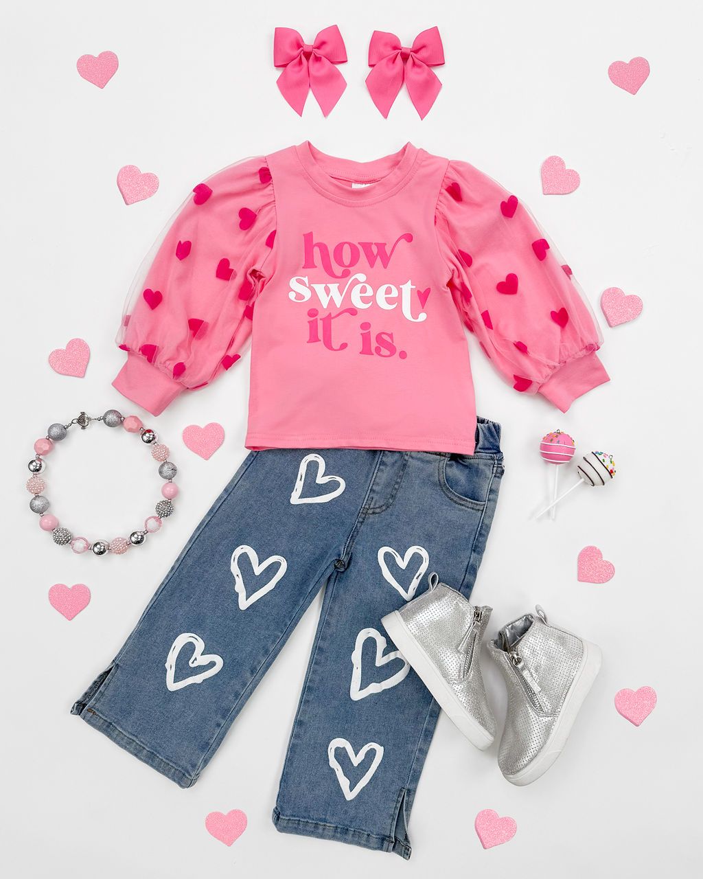 Pink heart-patterned shirt paired with denim jeans featuring white heart designs and matching accessories.