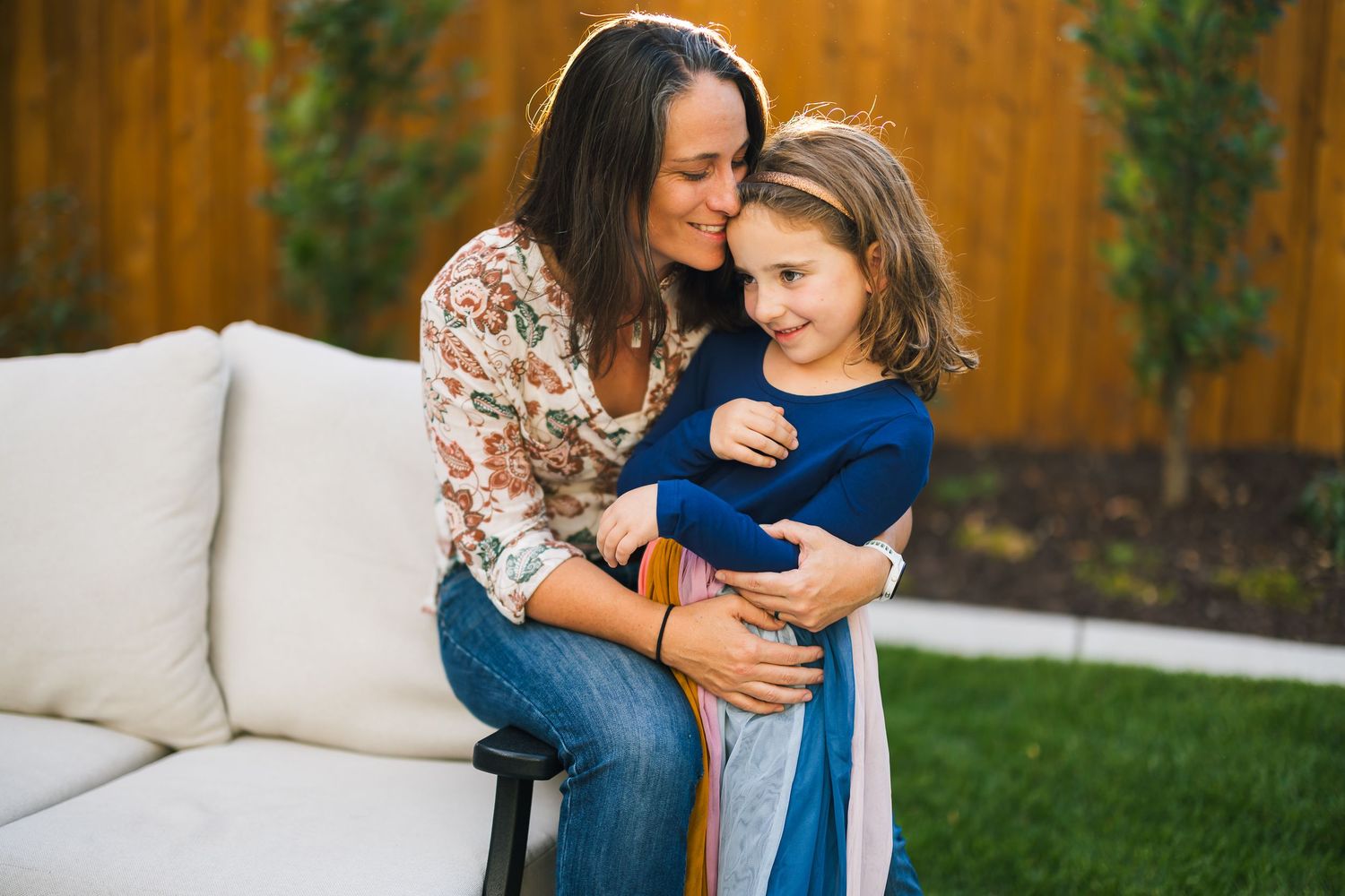 Mother and child sharing tender moment on outdoor patio sofa.