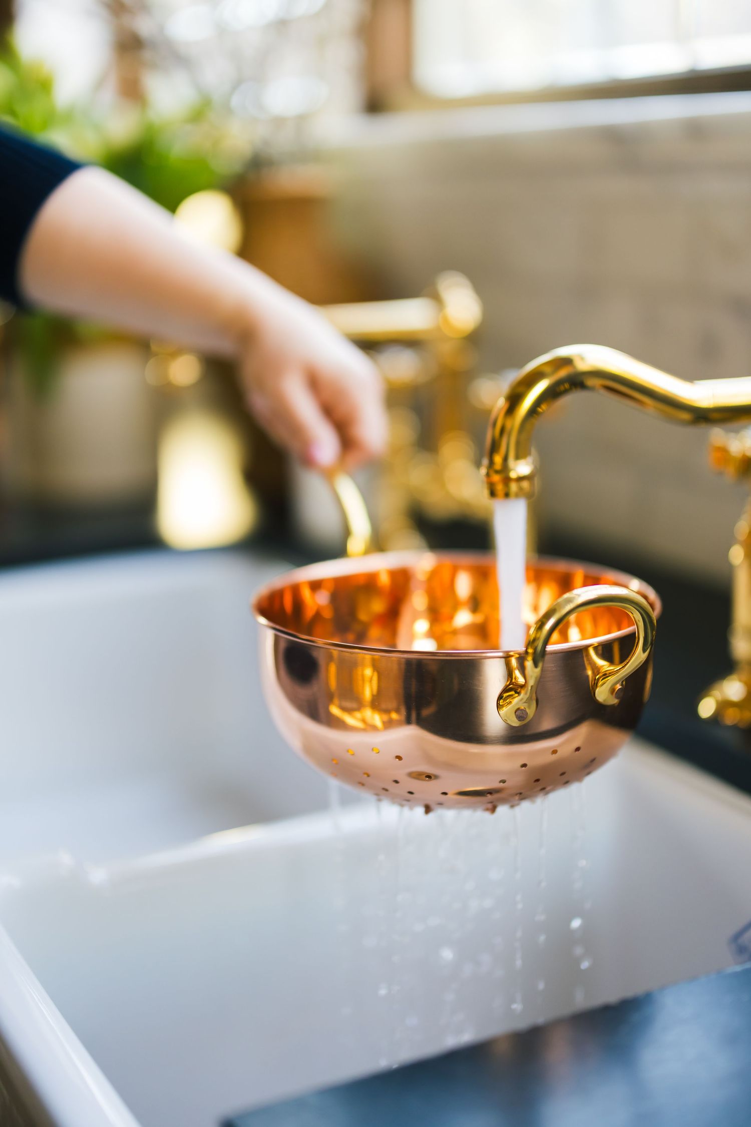 A copper ladle scoops clear liquid from a block of ice in an elegant cocktail preparation setup.