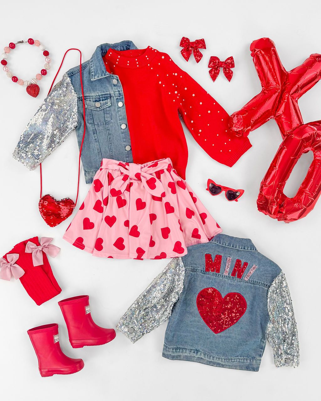 Children's Valentine's Day outfits featuring denim overalls, red dresses, and heart patterns laid flat.