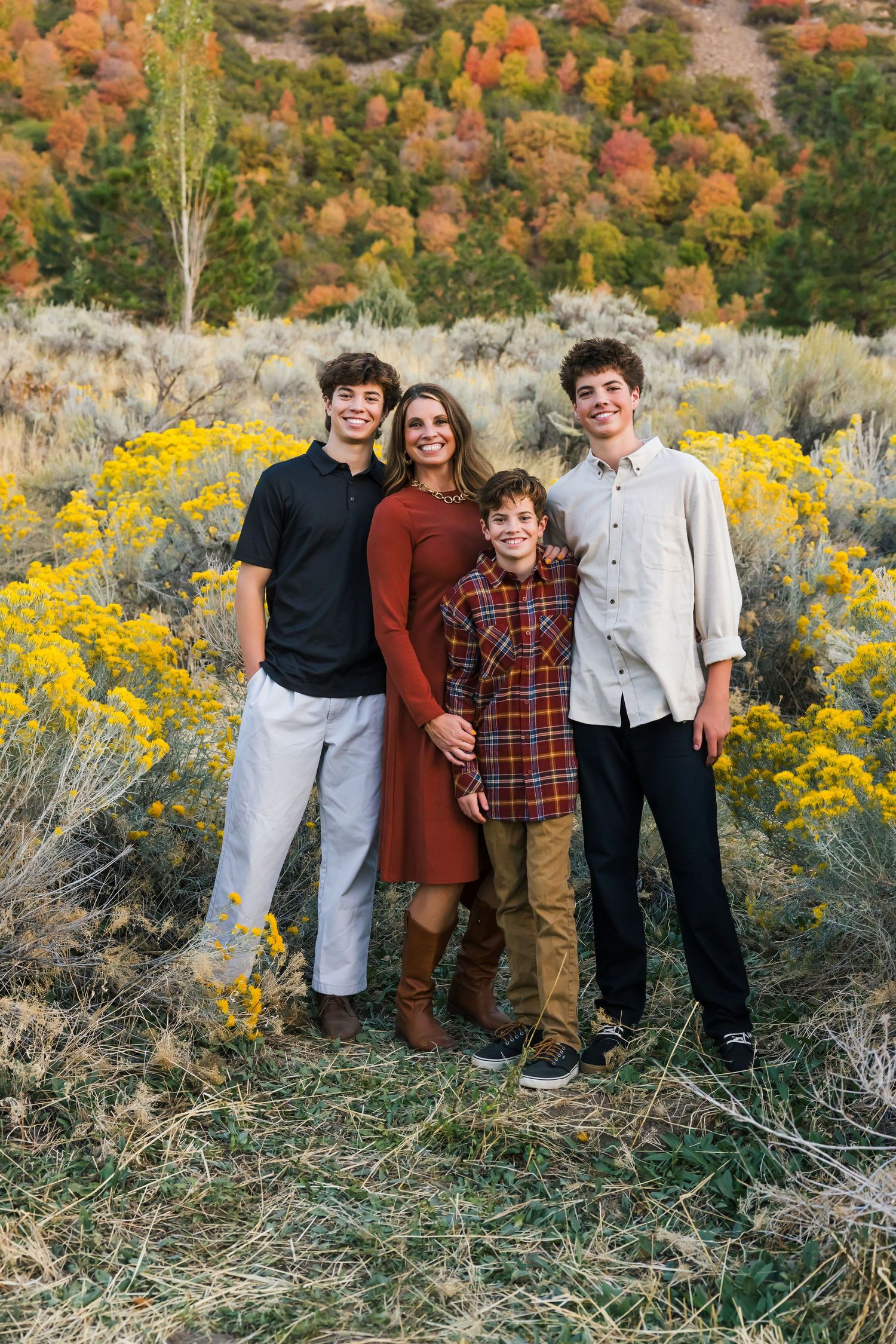 Family group poses together among autumn foliage and yellow wildflowers of Sandy, Utah.
