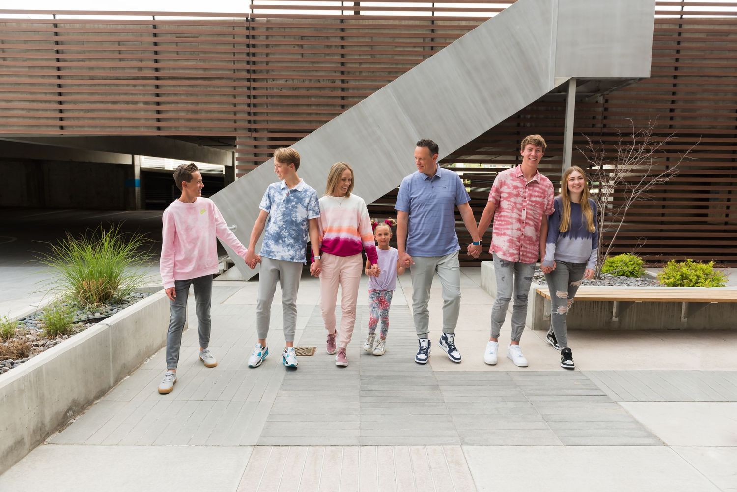 Line of people walking together against modern building wall in coordinated outfits.