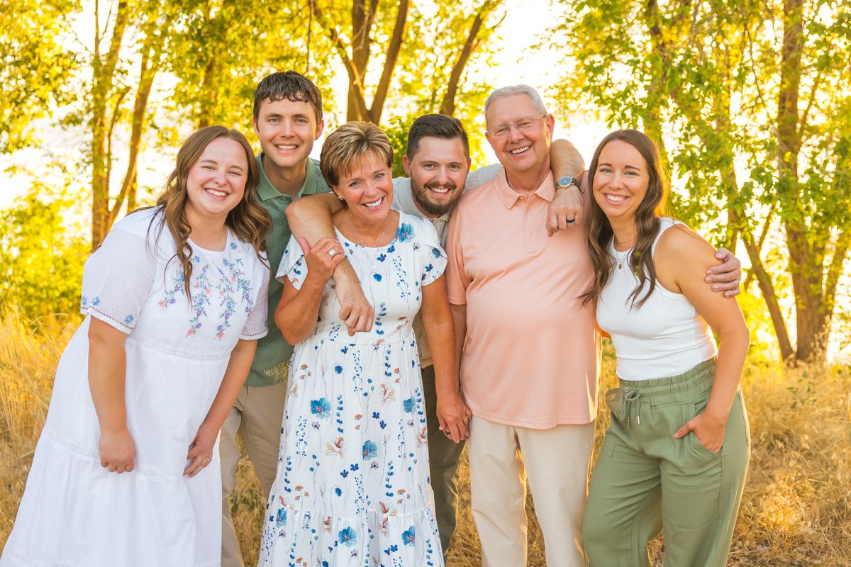 Extended family group photo in coordinated outfits during sunset.