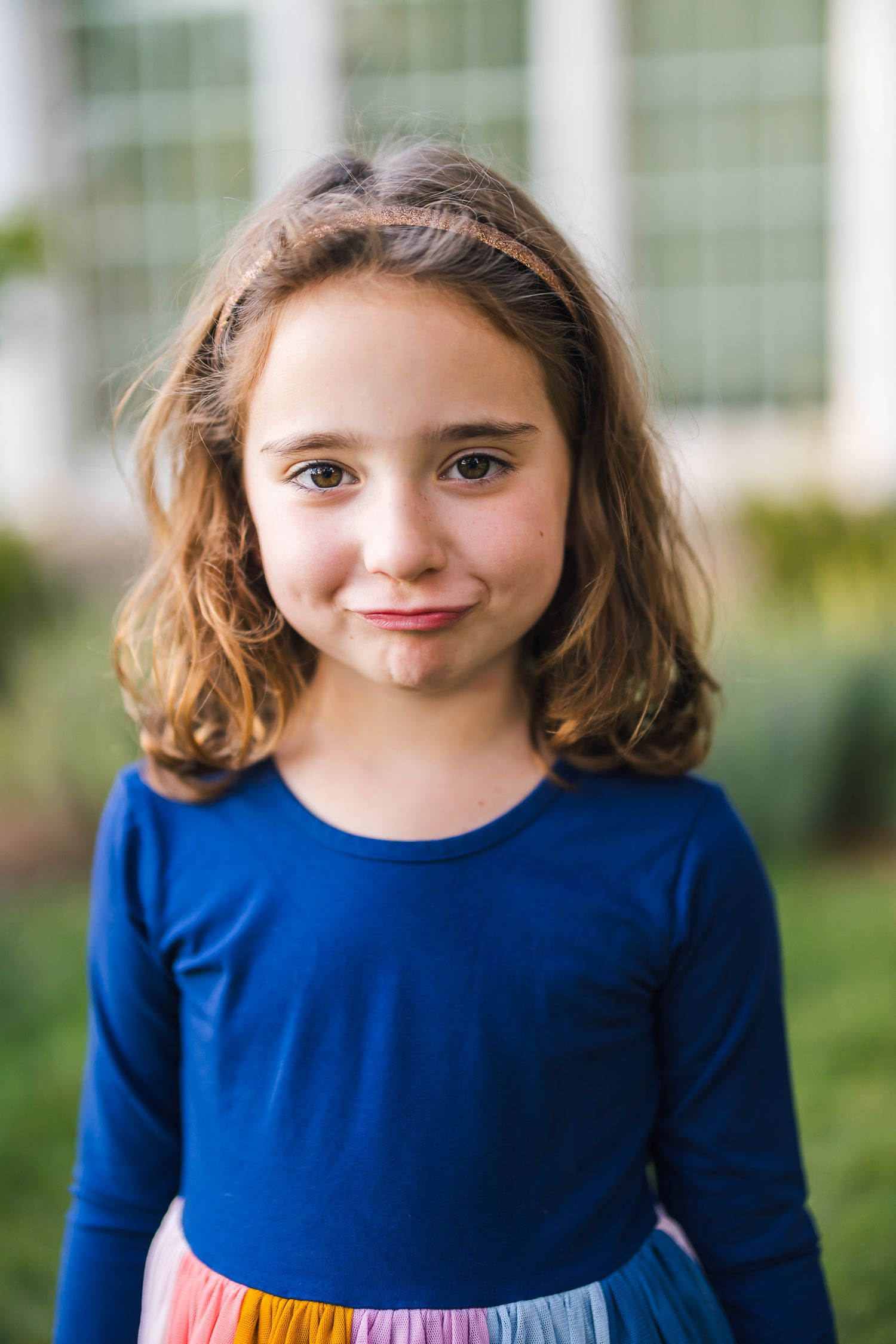 Portrait of a young girl wearing a blue and rainbow dress outdoors.