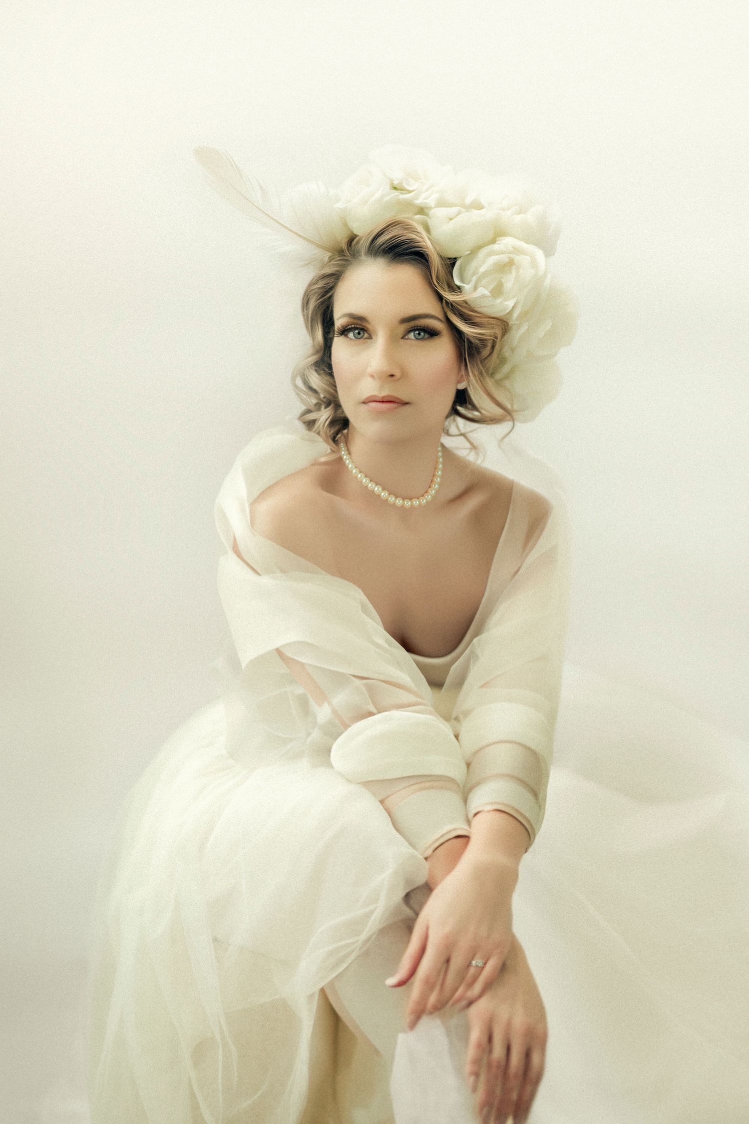 Ethereal bridal portraits in soft white tones with pearl accessories and flowing fabric.