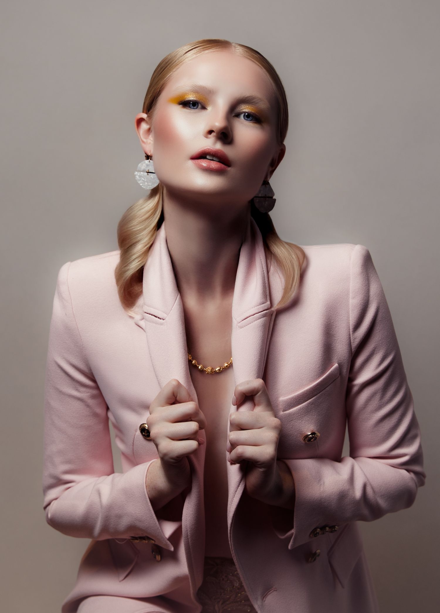 Fashion editorial featuring soft pink blazer and minimalist styling against neutral backdrop.